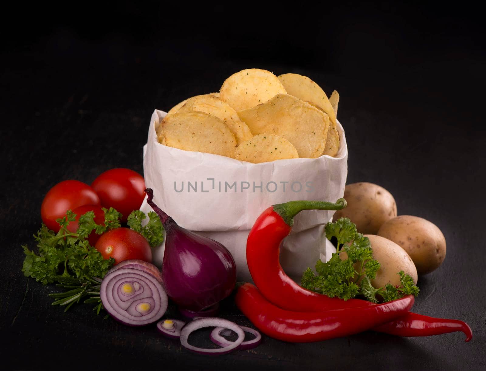 Potato chips on a dark wooden board. Fast food. Dark background. by aprilphoto