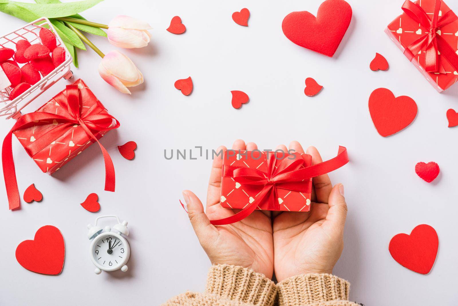 Valentine's day and birthday. Woman hands holding gift or present box decorated and red heart surprise on white background, Female's hand hold gift box package in craft paper Top view flat lay