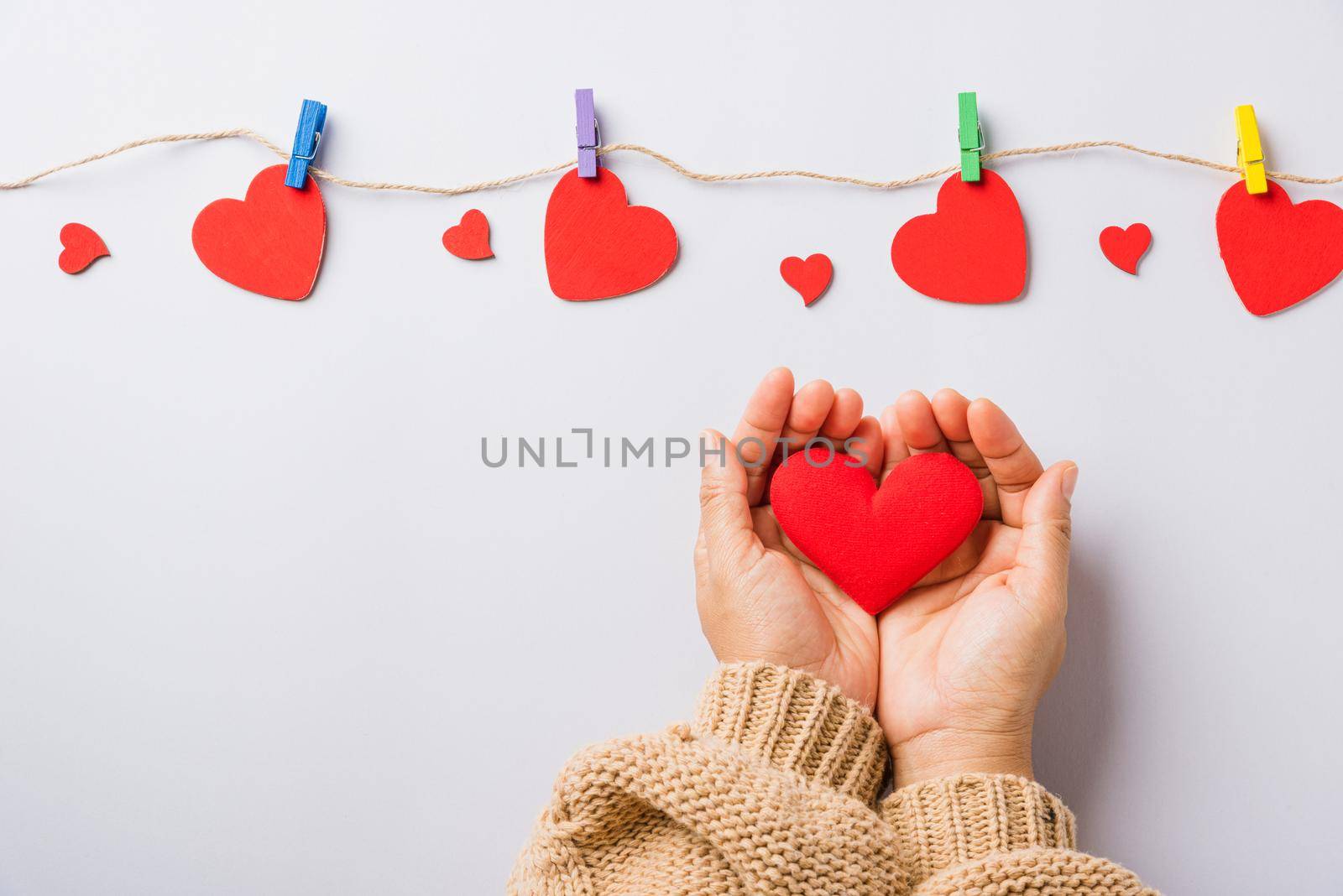 Valentine's day and birthday. Woman hands holding red heart present decorated surprise on white background, Female's hand hold gift heart on hands, Top view flat lay composition