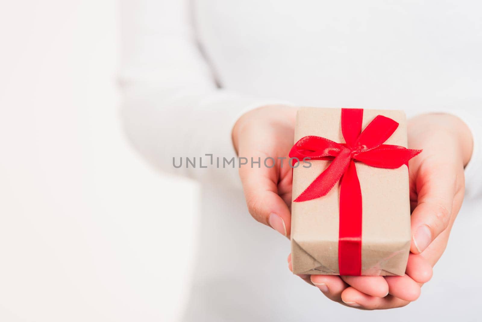 Valentine Day. Female beauty hands holding small gift package box present wrapped paper with ribbon isolated on white background, Christmas, New year, Birthday holiday background concept