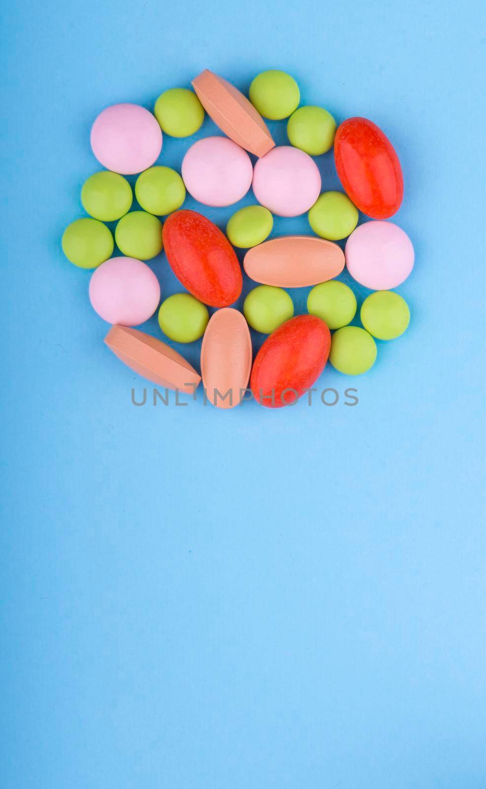 Colored pills, tablets and capsules on a blue background.