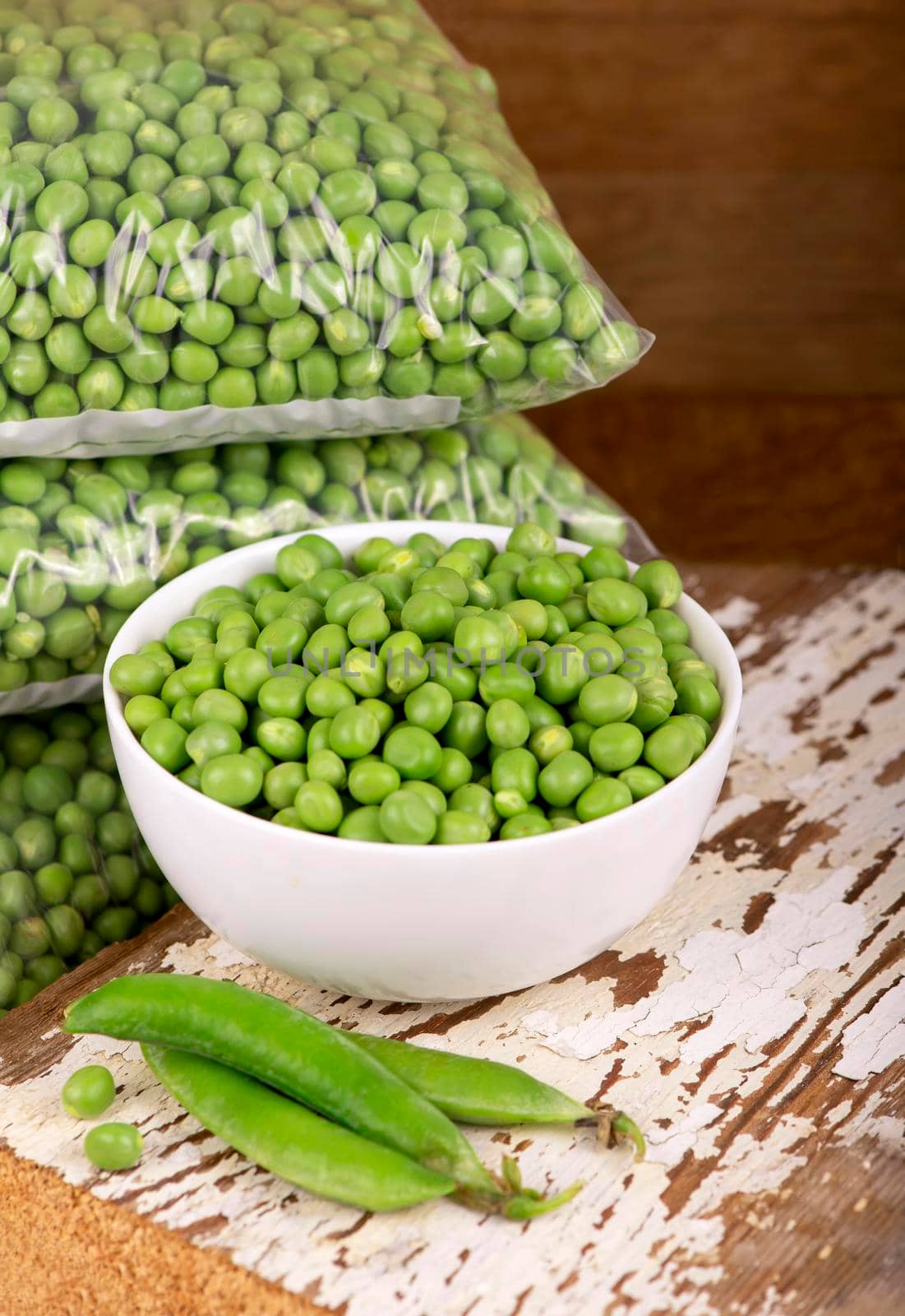 RAW baby peas in small white bowl, over retro wooden boards. Close-up