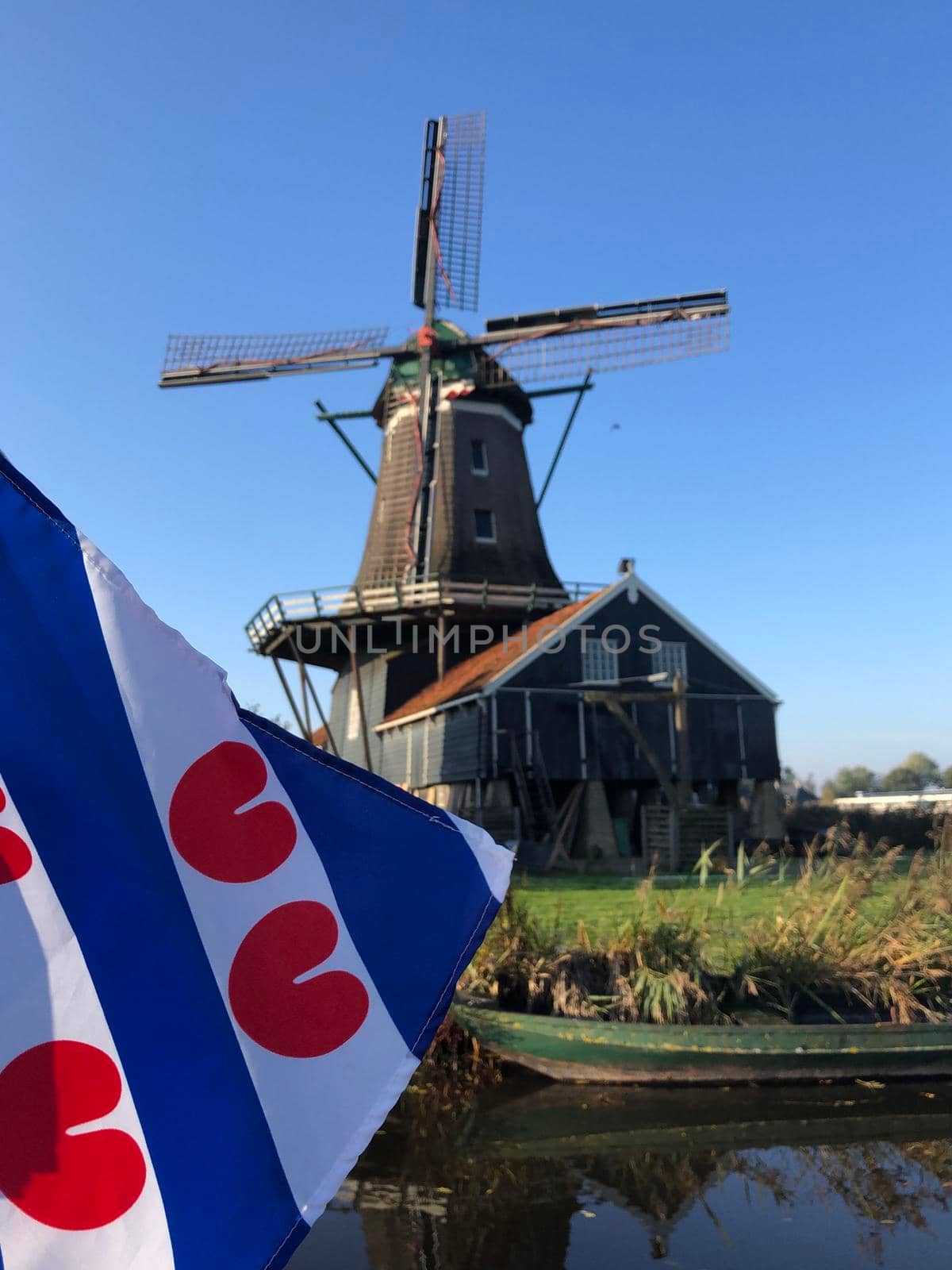 Frisian flag in front of the windmill in IJlst during autumn in Friesland, The Netherlands