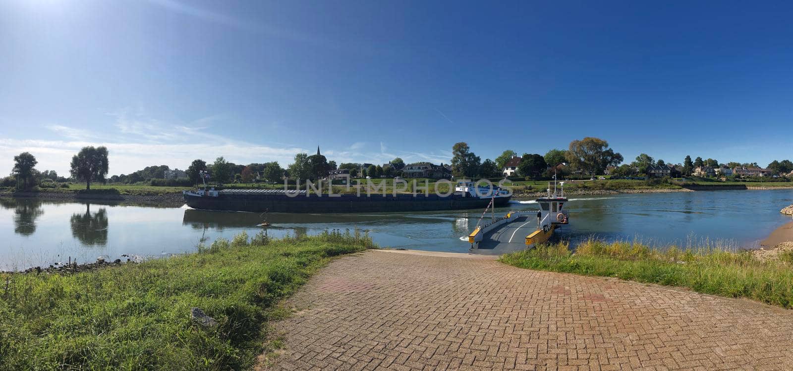 Ferry and cargo ship at the IJssel river between Olburgen and Dieren, Gelderland The Netherlands