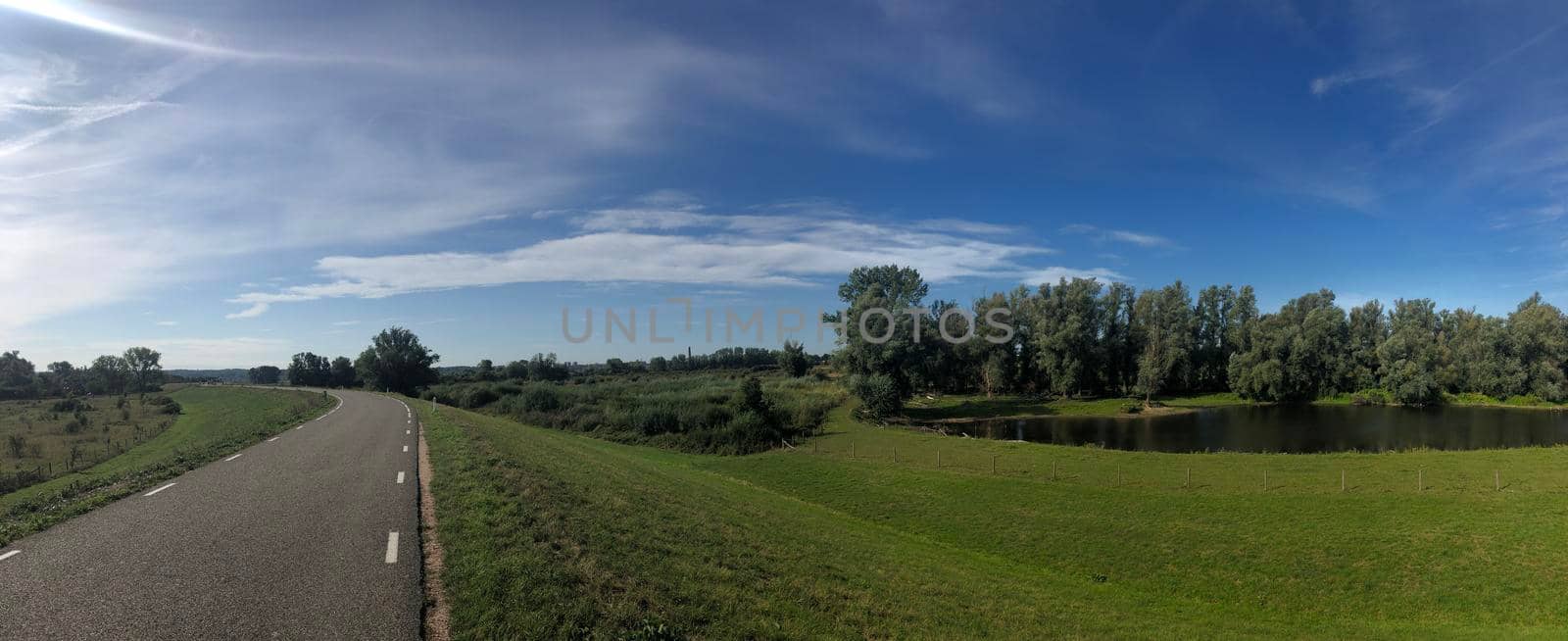 Road on a dyke around Ooij in Gelderland  by traveltelly