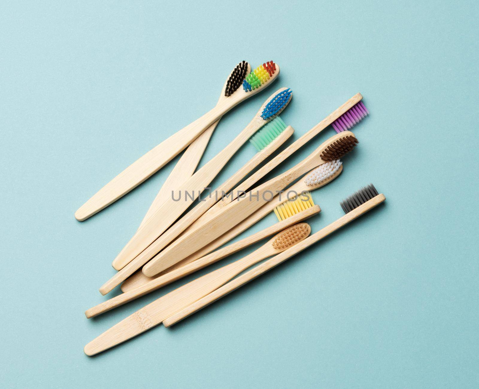 multicolored wooden toothbrushes on a blue background, plastic rejection concept, zero waste, top view