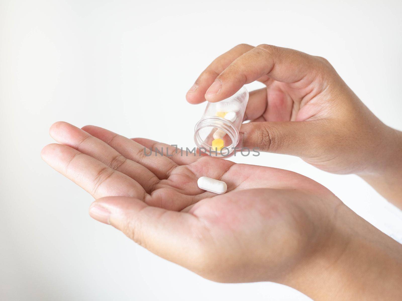 A woman pouring medicine onto her hand from a bottle On a white background