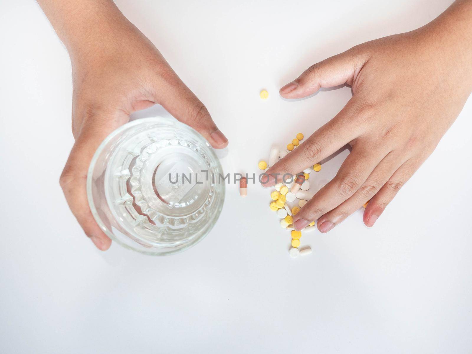 A woman with her hand on the drug The other hand was picking up a glass of water. by Kulpreya