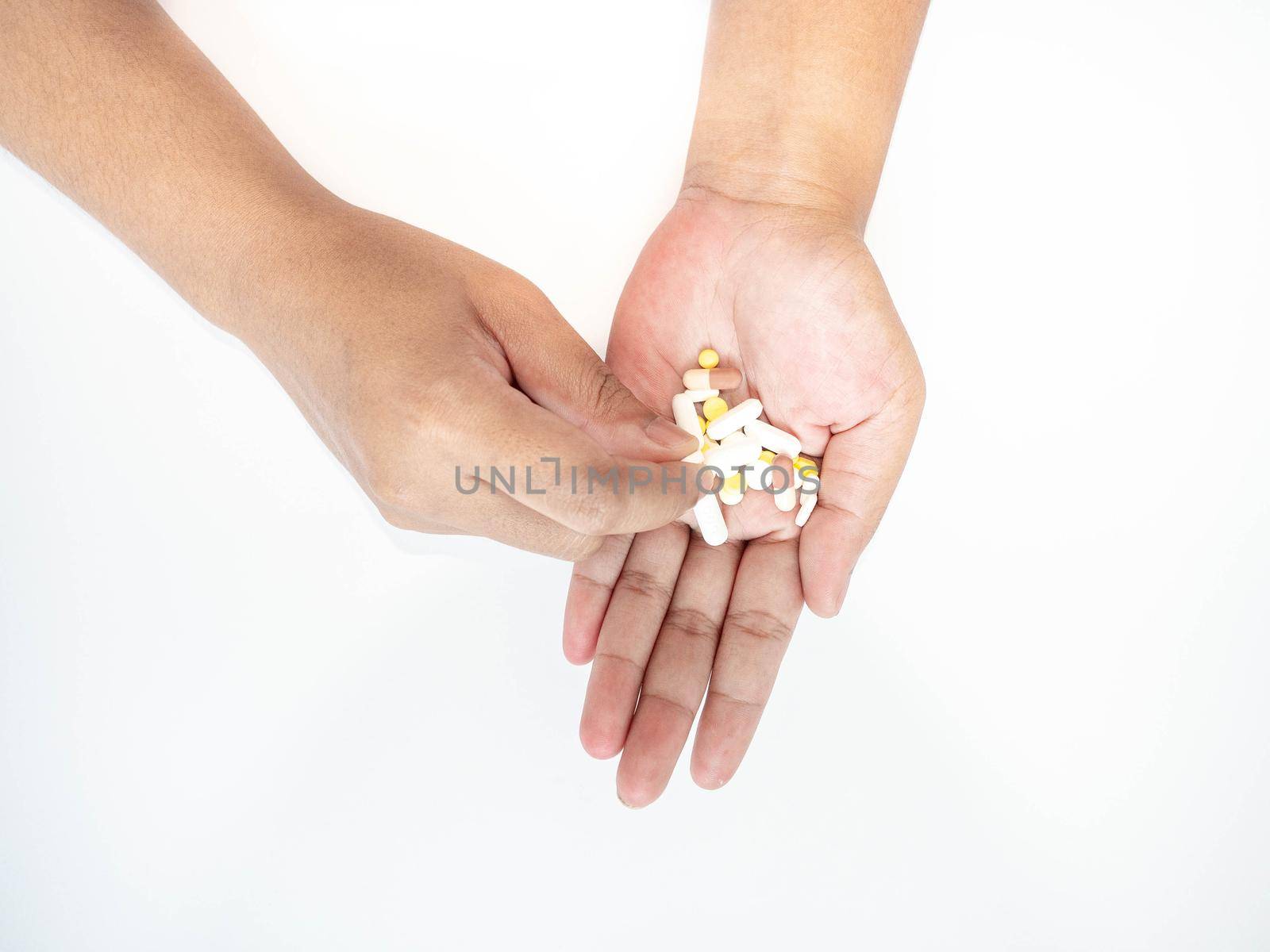 A woman picks up a pill from her hand White background. by Kulpreya