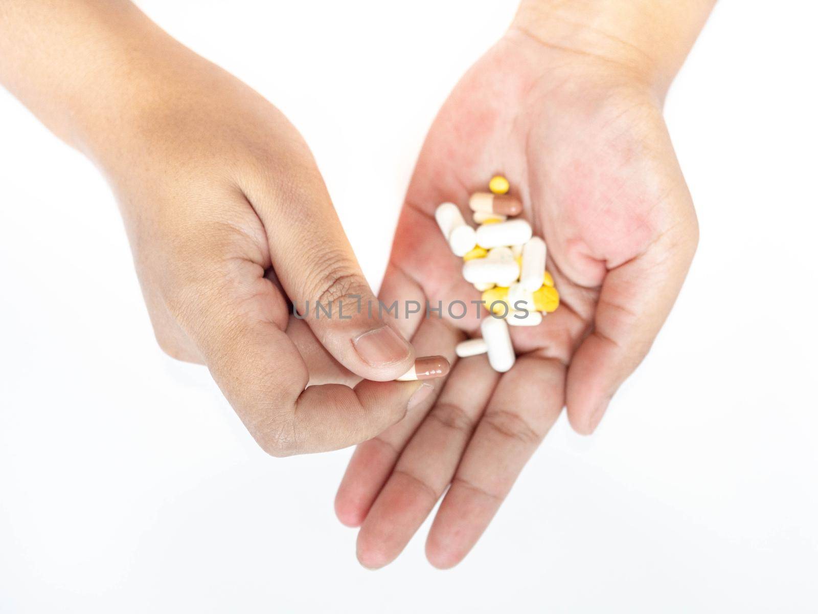 A woman picks up a pill from her hand White background.