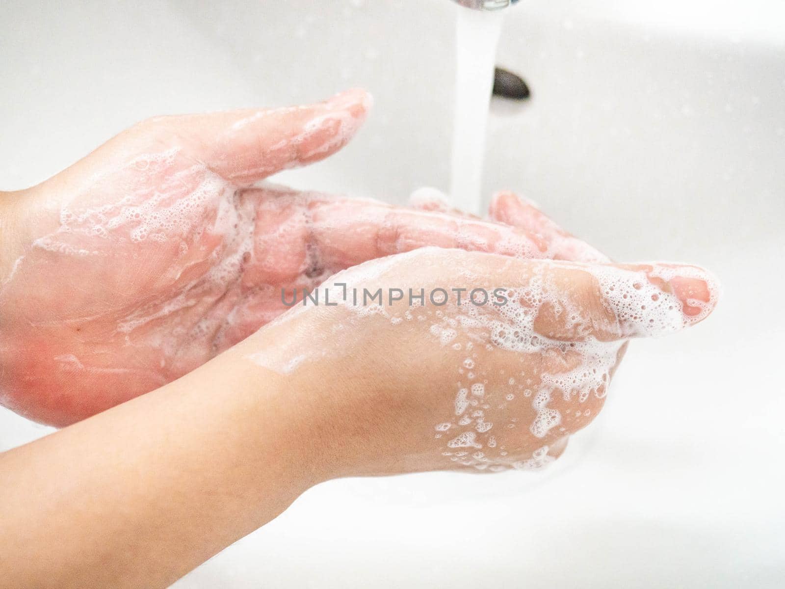 A woman cleaning hands Use hand soap until white bubbles form in the basin.