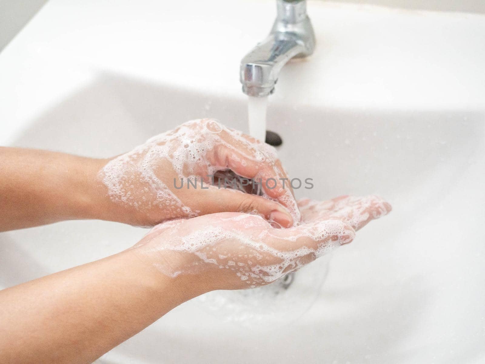 A woman cleaning hands Use hand soap until white bubbles form in the basin. by Kulpreya