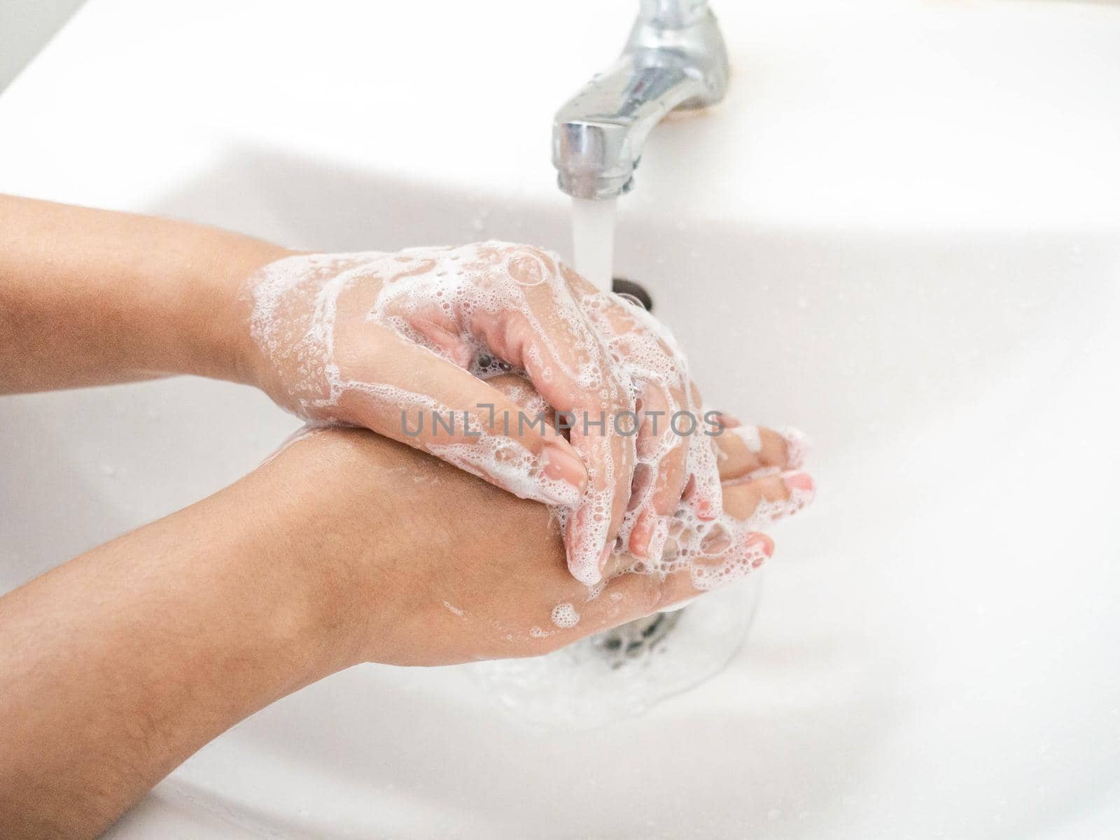 A woman cleaning hands Use hand soap until white bubbles form in the basin.