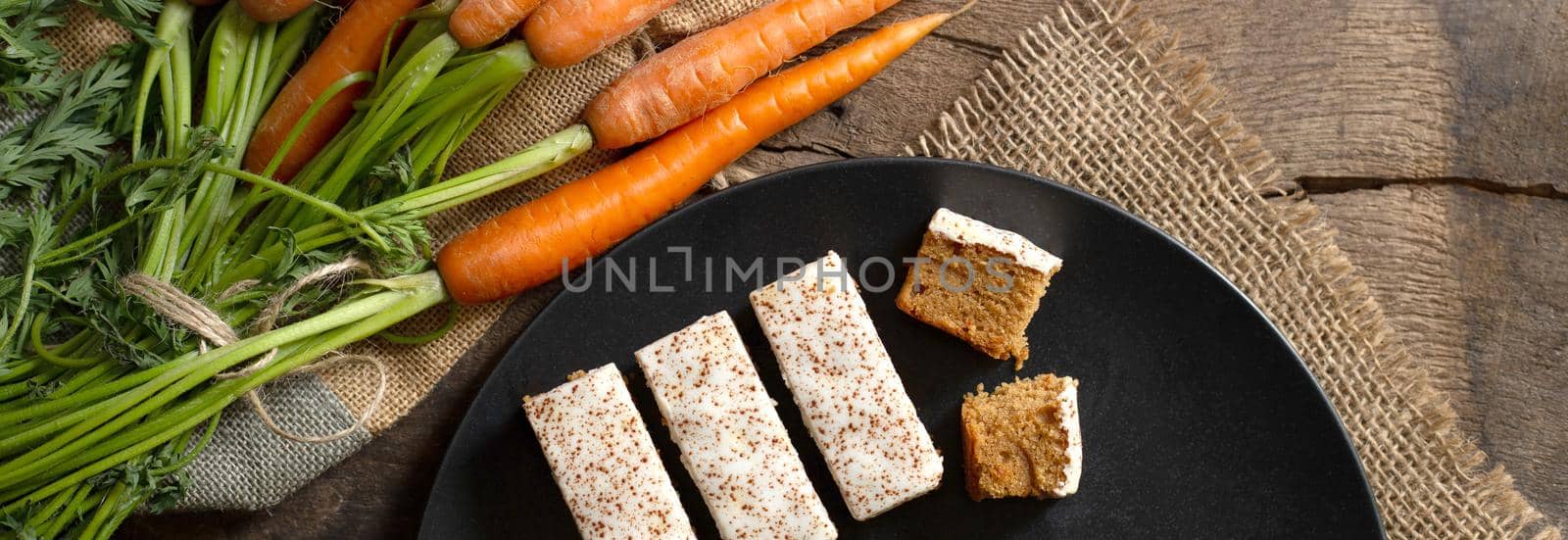 Fresh organic carrots, English carrots cakes on black plate, canvas on antique wooden table. Rustic kitchen concept. Banner, poster, mock up. Grunge, vintage, rustic style