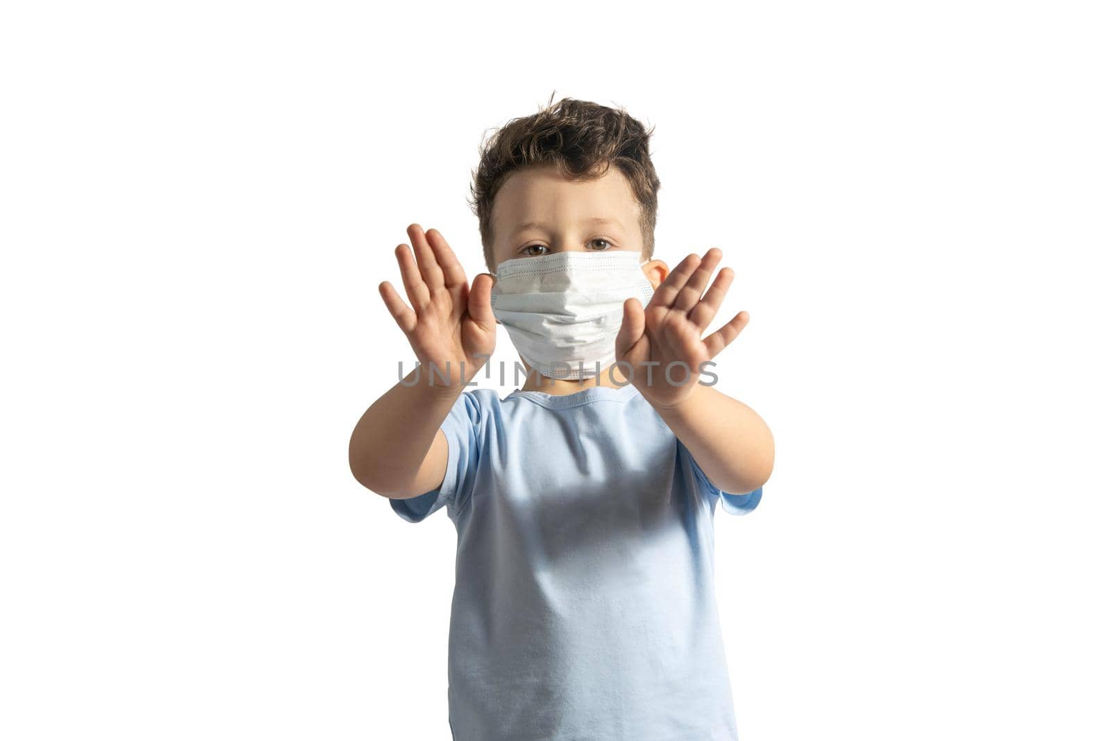 Concept of coronavirus quarantine. Child wearing medical protective mask during flu virus, making stop gesture. COVID-19. Small white boy doing stop sign with his hands, isolated on white by uspmen