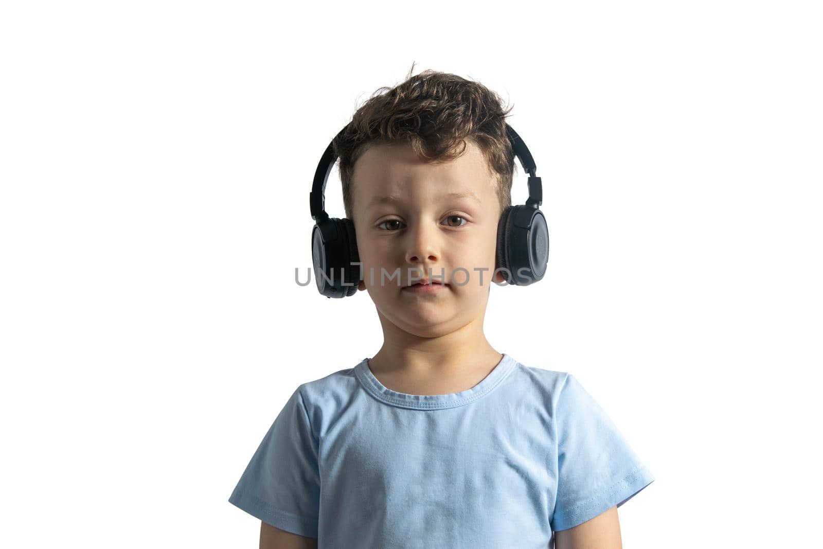 A beautiful European boy listens to music with headphones. Music lover since childhood. DJ. Isolated on white background.