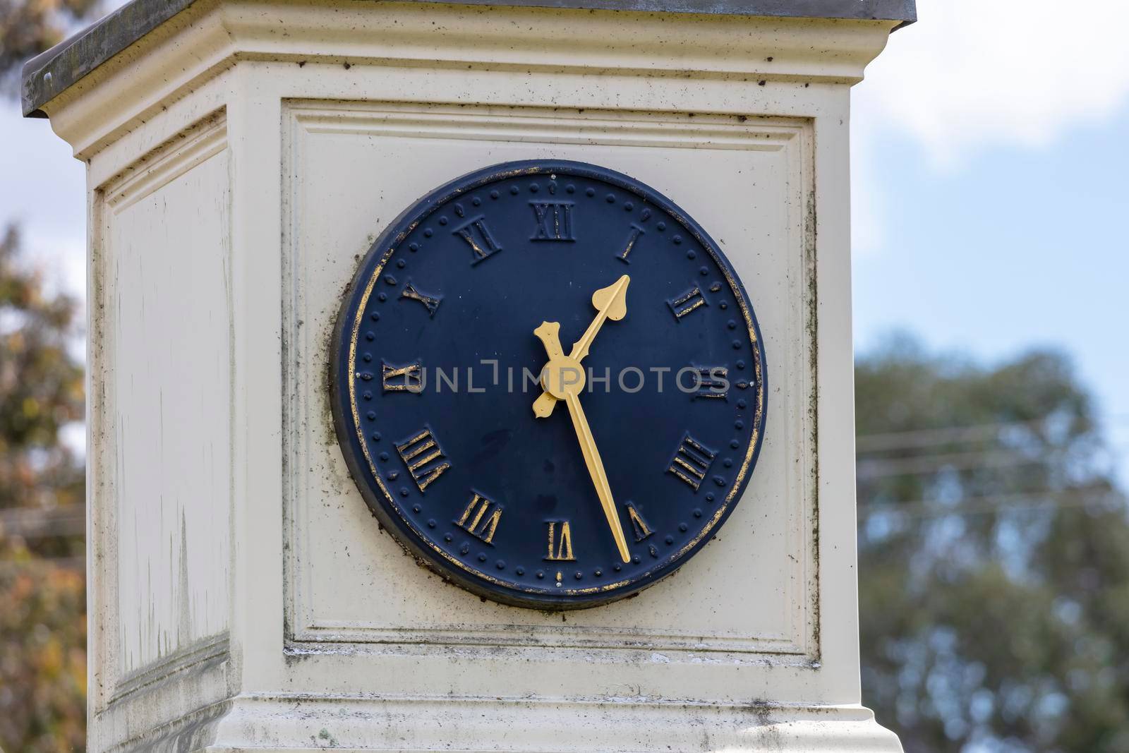 An old blue outdoor clock face with golden hands on a white background by WittkePhotos