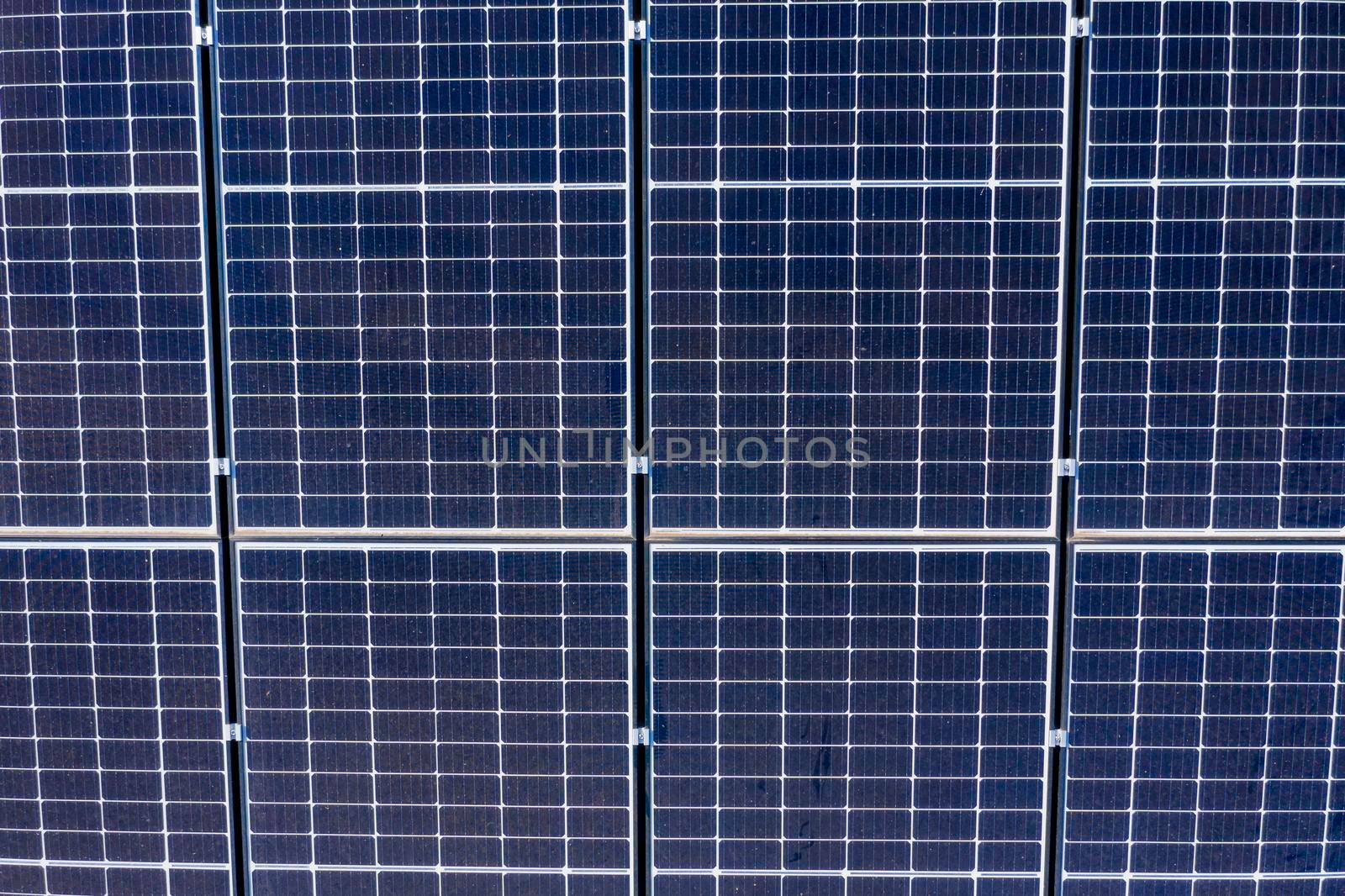 Aerial view of blue solar panels in a square grid pattern on a residential roof
