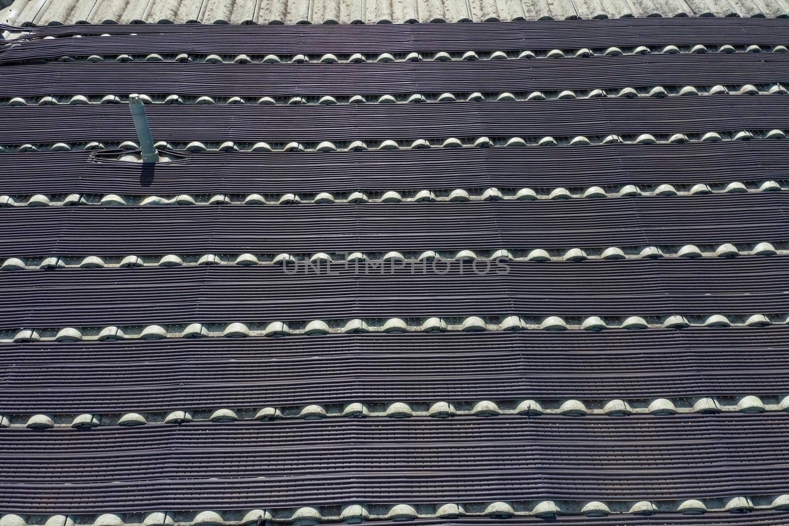 Hot water pipes on a green tiled roof in the bright sunshine. by WittkePhotos