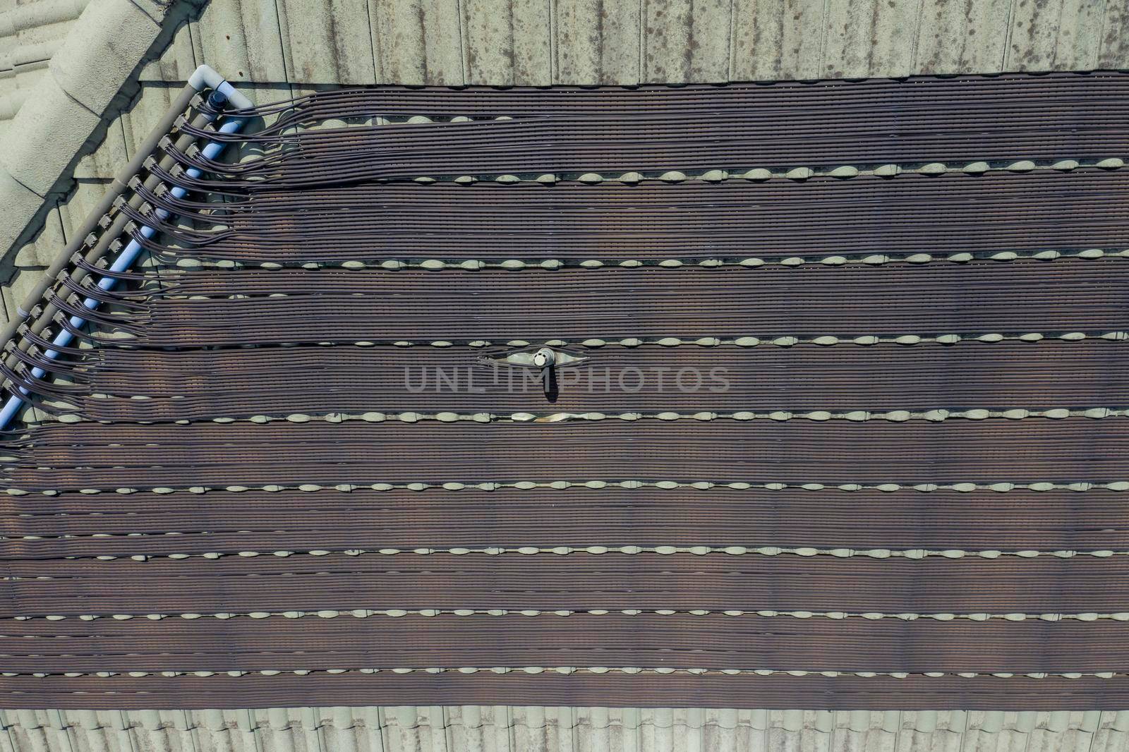 Hot water pipes on a green tiled roof in the bright sunshine. by WittkePhotos