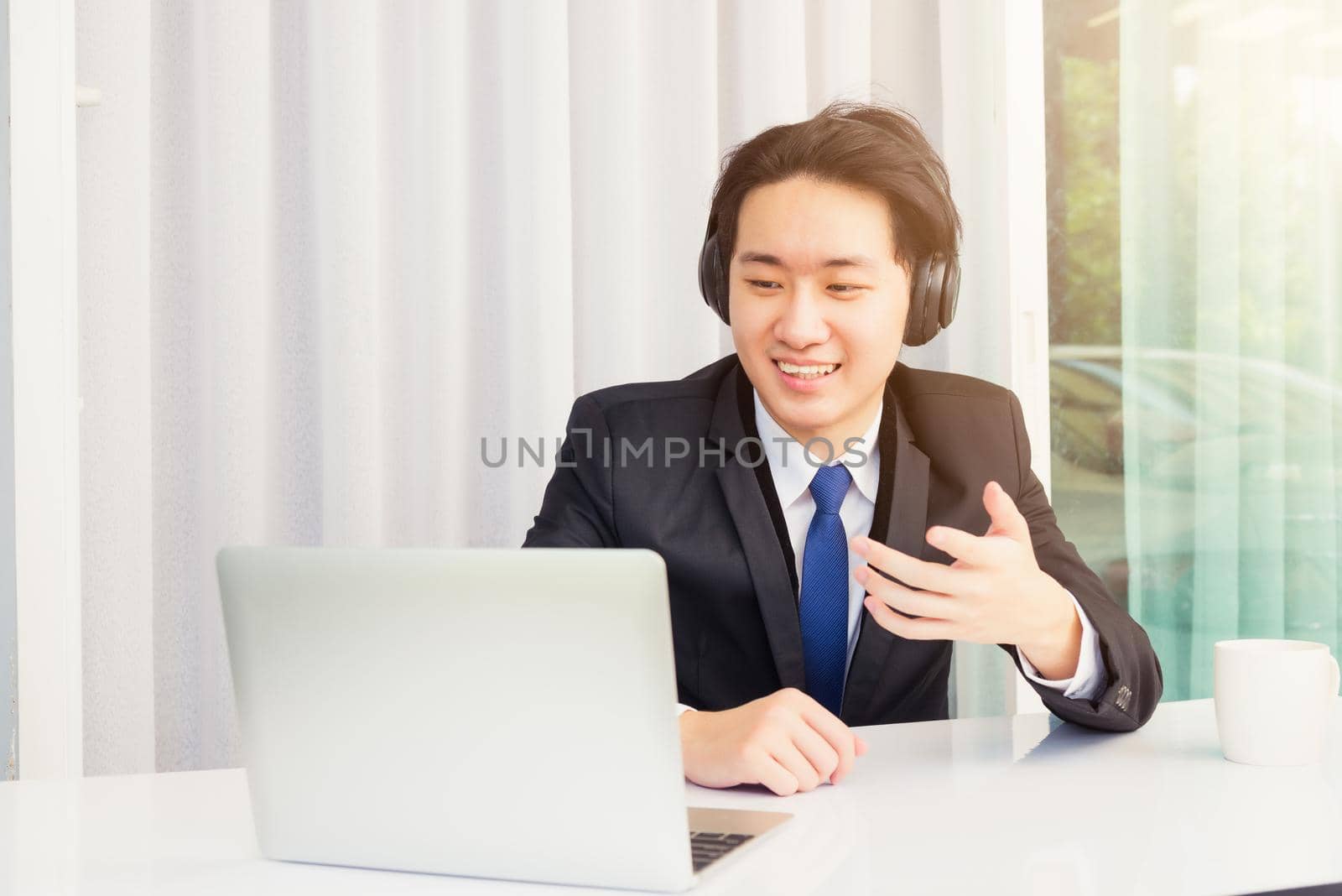 Asian young businessman smile wearing headphones and suit video conference call by Sorapop