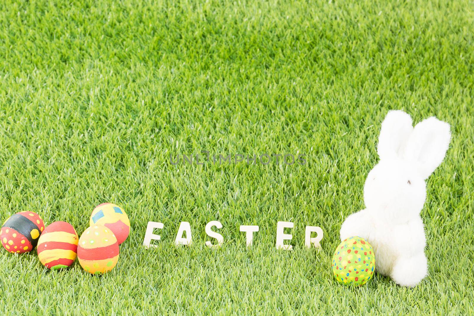 Easter bunny toy and Easter eggs with text on green grass