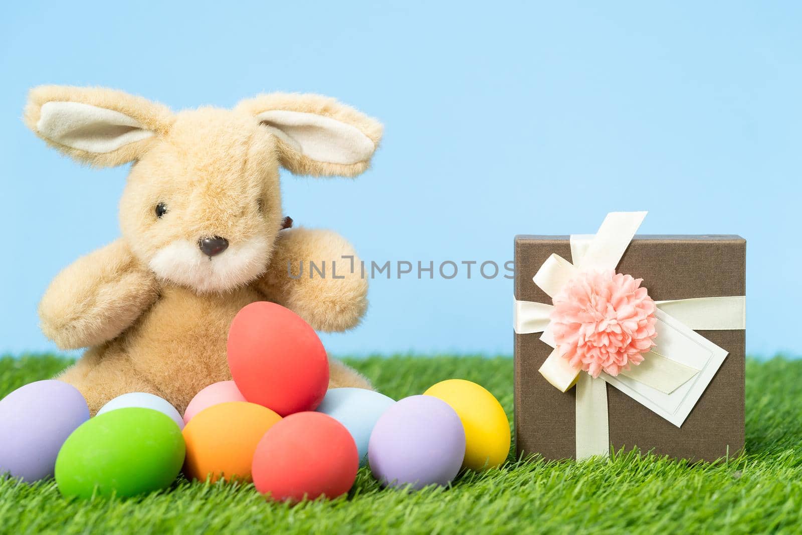 Colorful Easter eggs and gift box on grass  with blue background