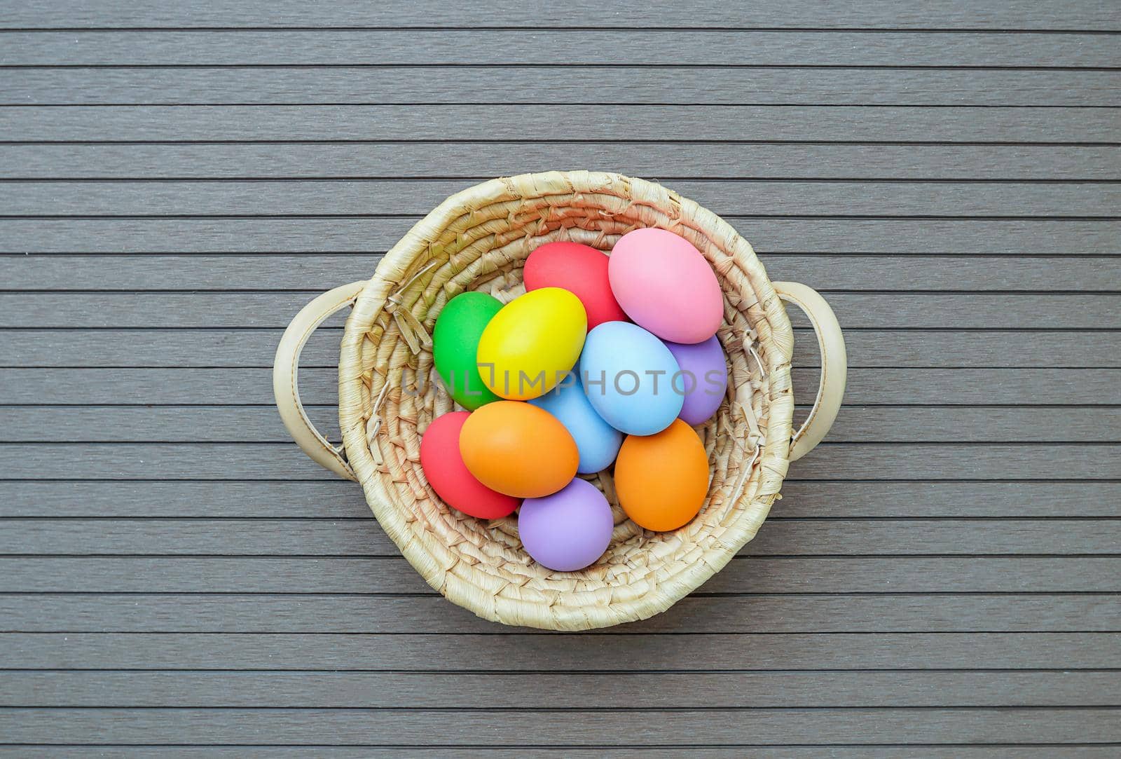 Colorful easter eggs in the basket on wood background with space