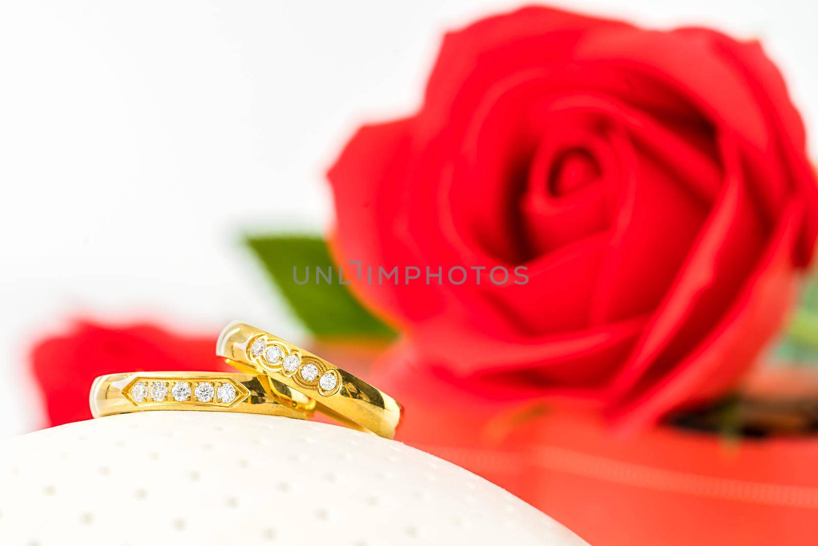 Red plastic fake roses on white background, Wedding concept with roses and gold rings