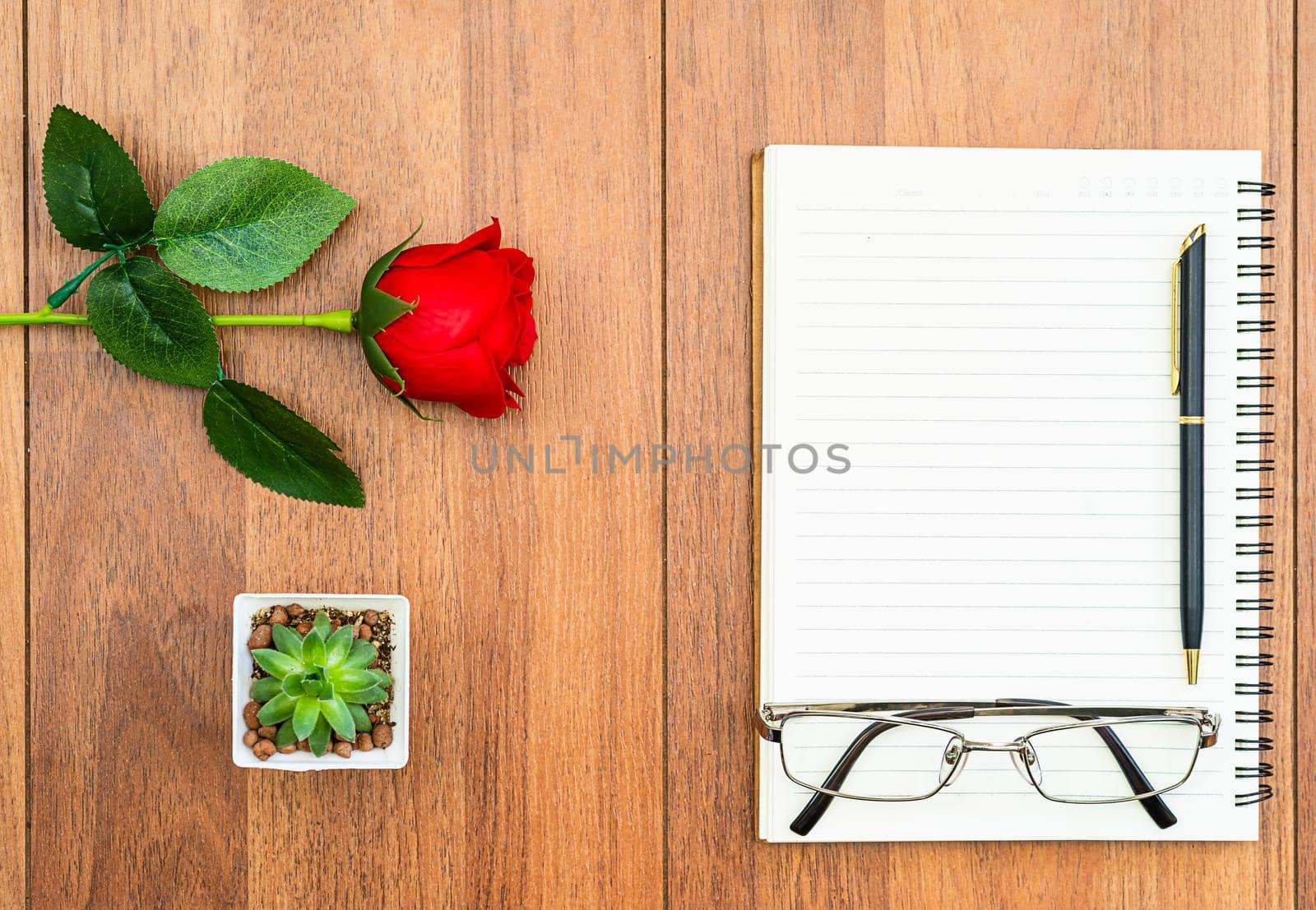 Top view Red roses on wooden table and pen on notepad on wood deck ,Valentines day concept