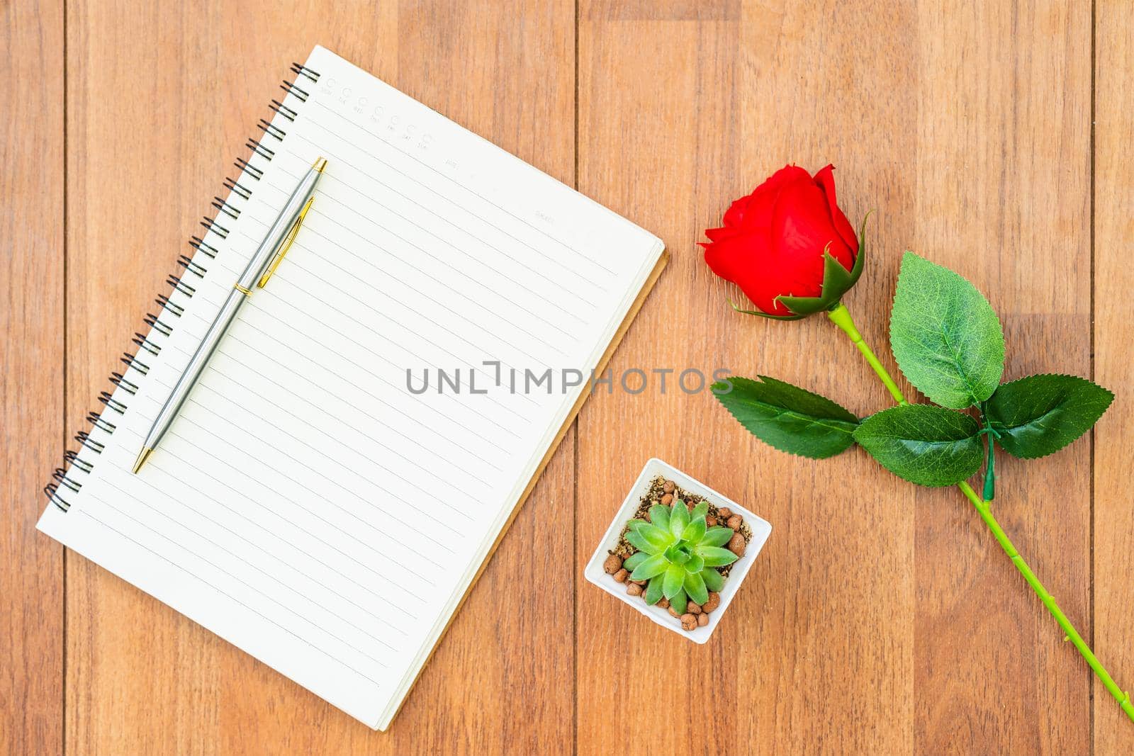 Top view Red roses on wooden table and pen on notepad on wood deck ,Valentines day concept