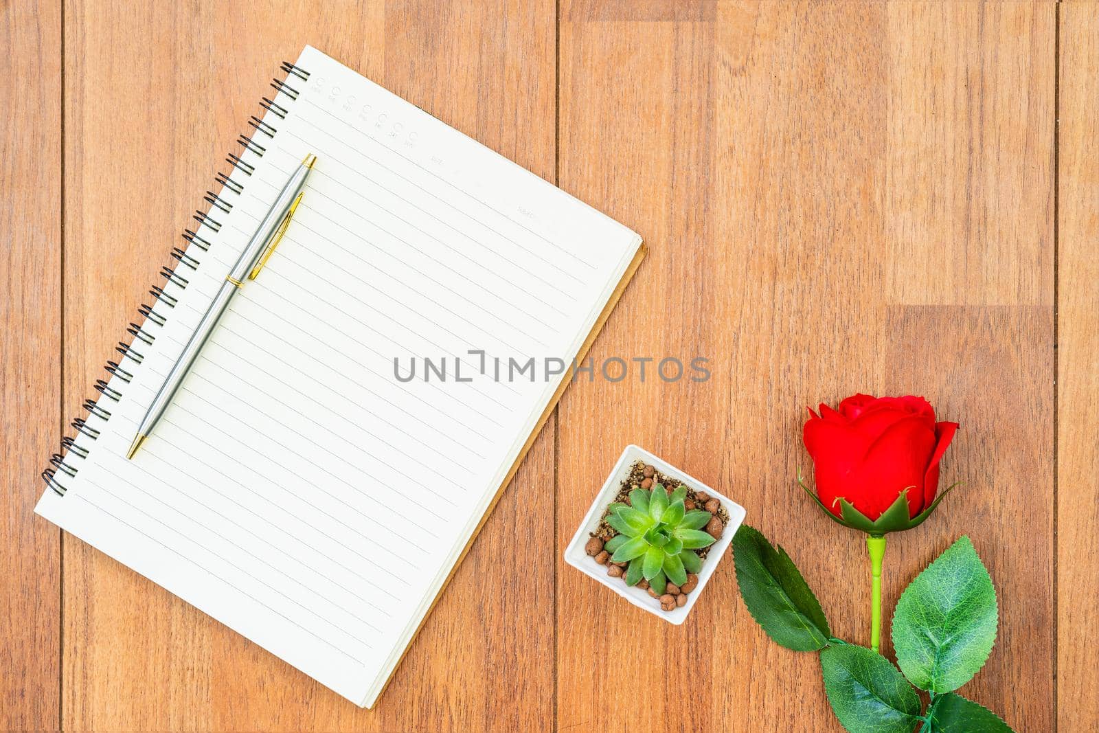 Top view Red roses on wooden table and pen on notepad on wood deck ,Valentines day concept