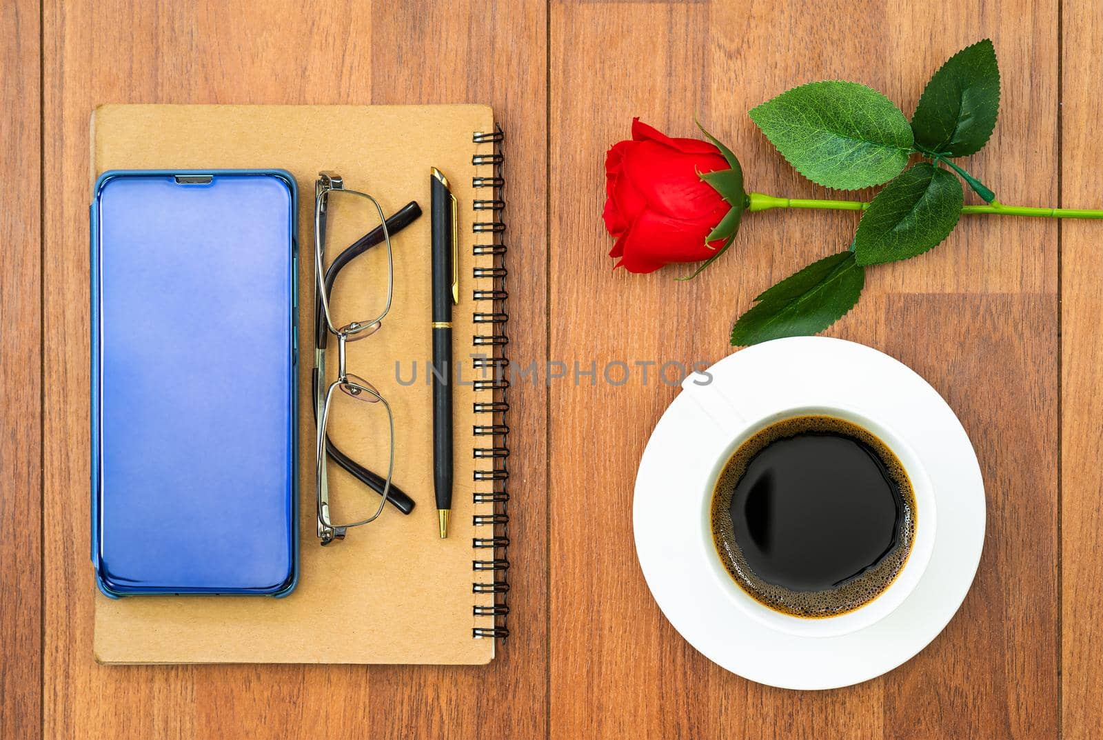 Top view image of coffee cup ,notebook and cellphone with eye glasse on wooden table background for adding text or mockup