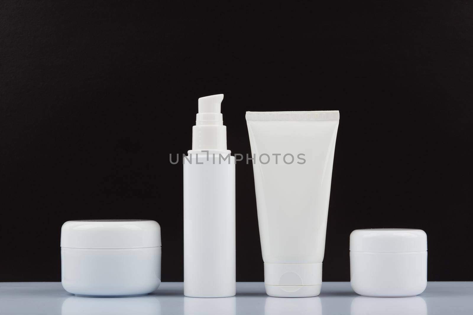 Horizontal still life with white cream tubes on white table against dark brown background. Concept of male skincare with copy space. High quality photo