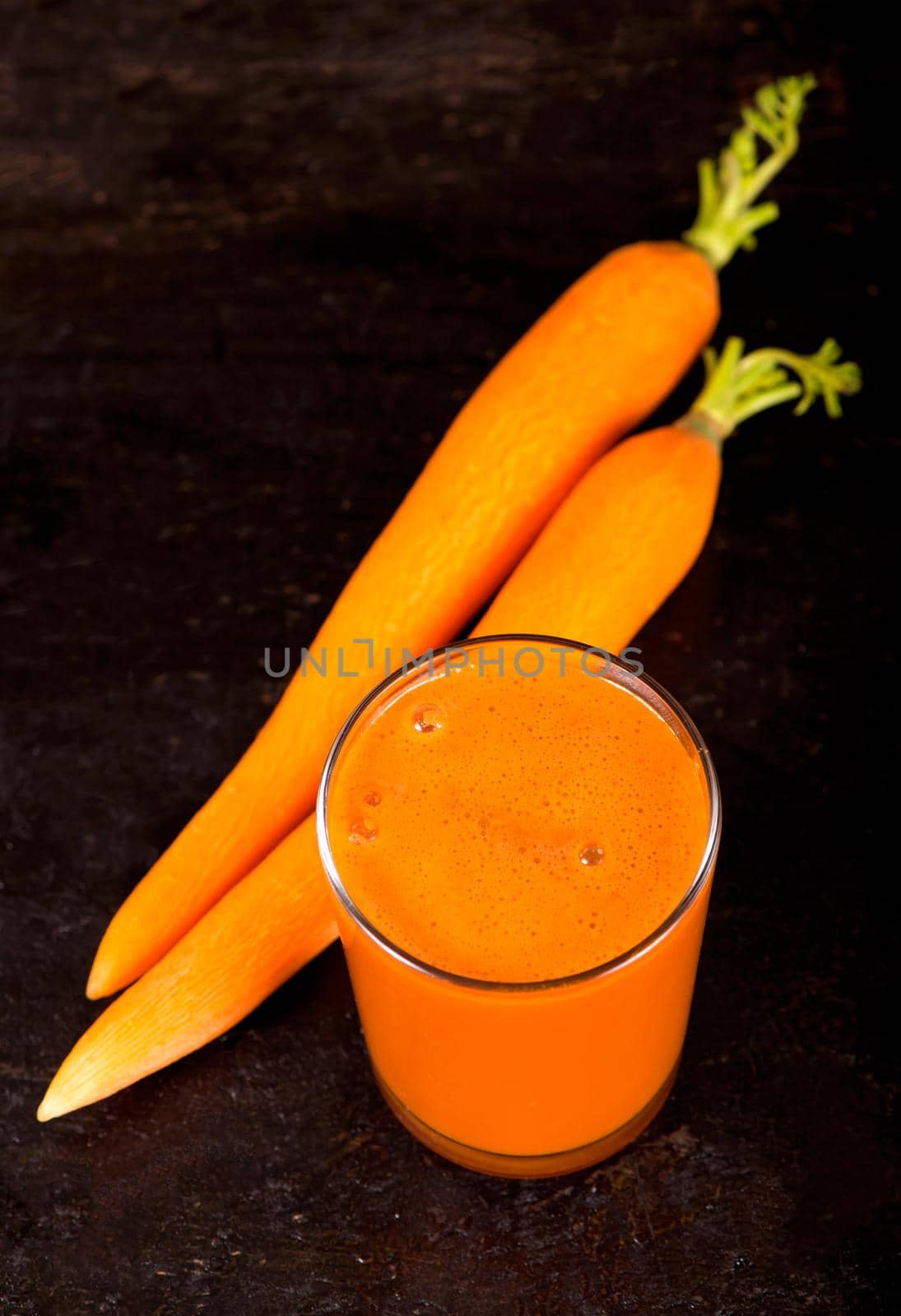Fresh squeezed carrot juice on wooden background