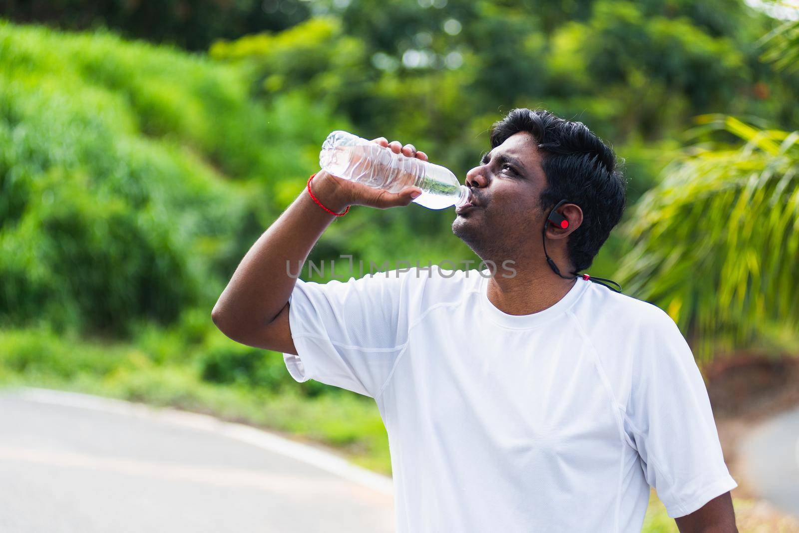sport runner black man wear athlete headphones he drinking water from a bottle by Sorapop