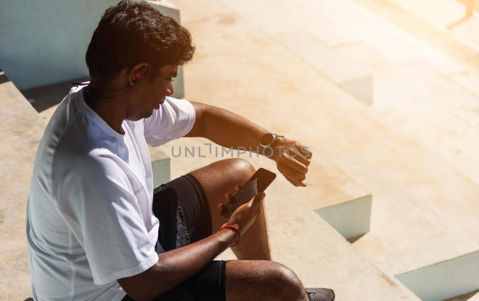 Close up Asian young athlete sport runner black man wear modern time smart watch and sync to a smartphone check running result after a training run at the outdoor, healthy exercise workout technology