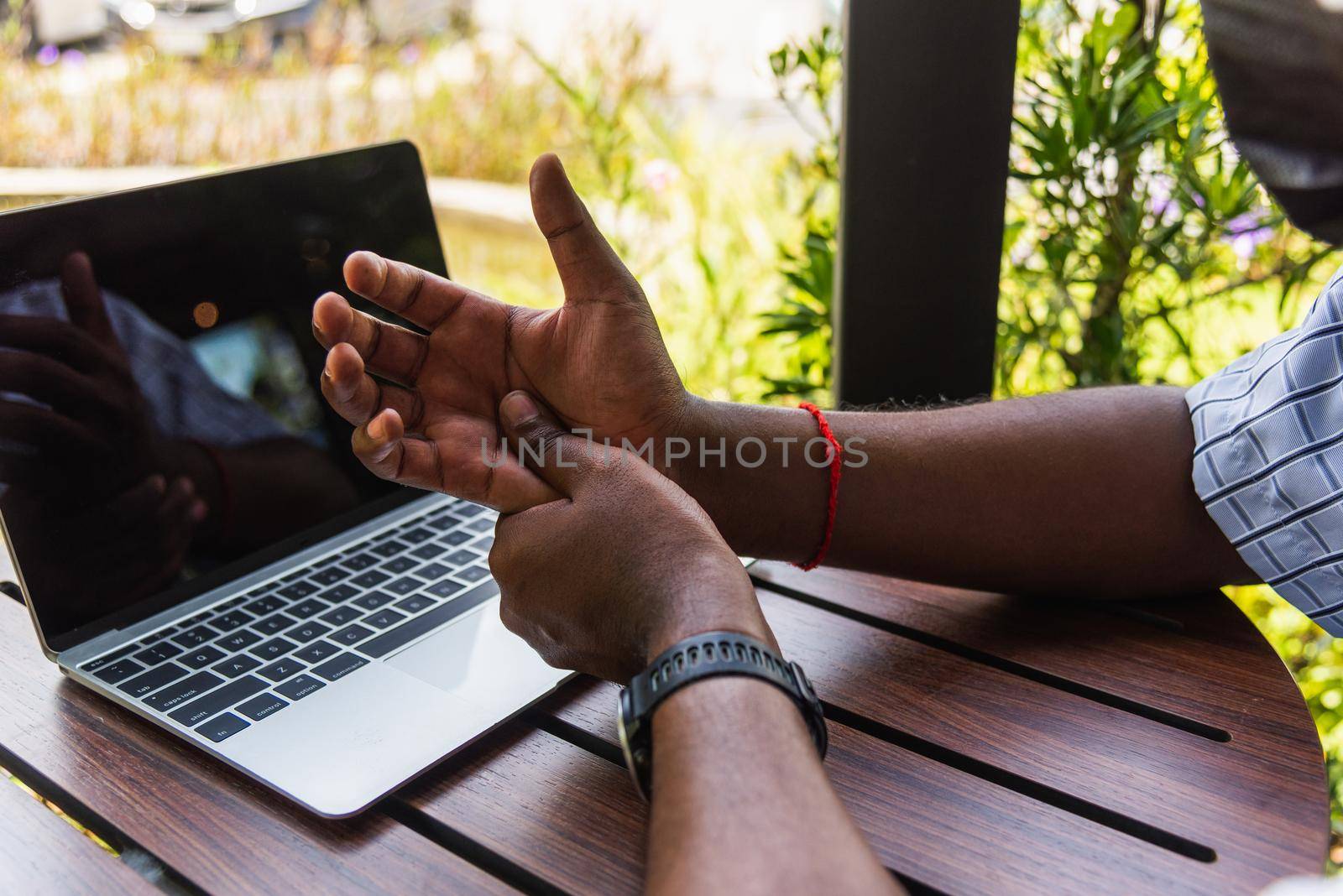 Closeup hands the Asian black man holding his wrist pain from using laptop computer he working long time, Injury office syndrome hand pain by occupational disease concept