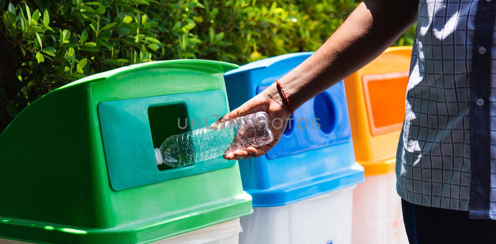 black hand throwing an empty plastic water bottle in the recycling garbage trash by Sorapop