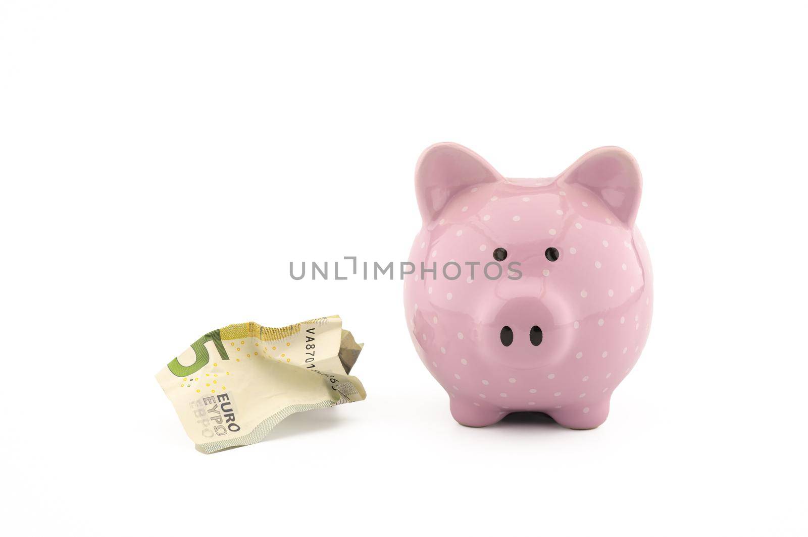 Crumpled banknotes of the euro and cute pink piggy bank on white with copy space for financial or savings concepts