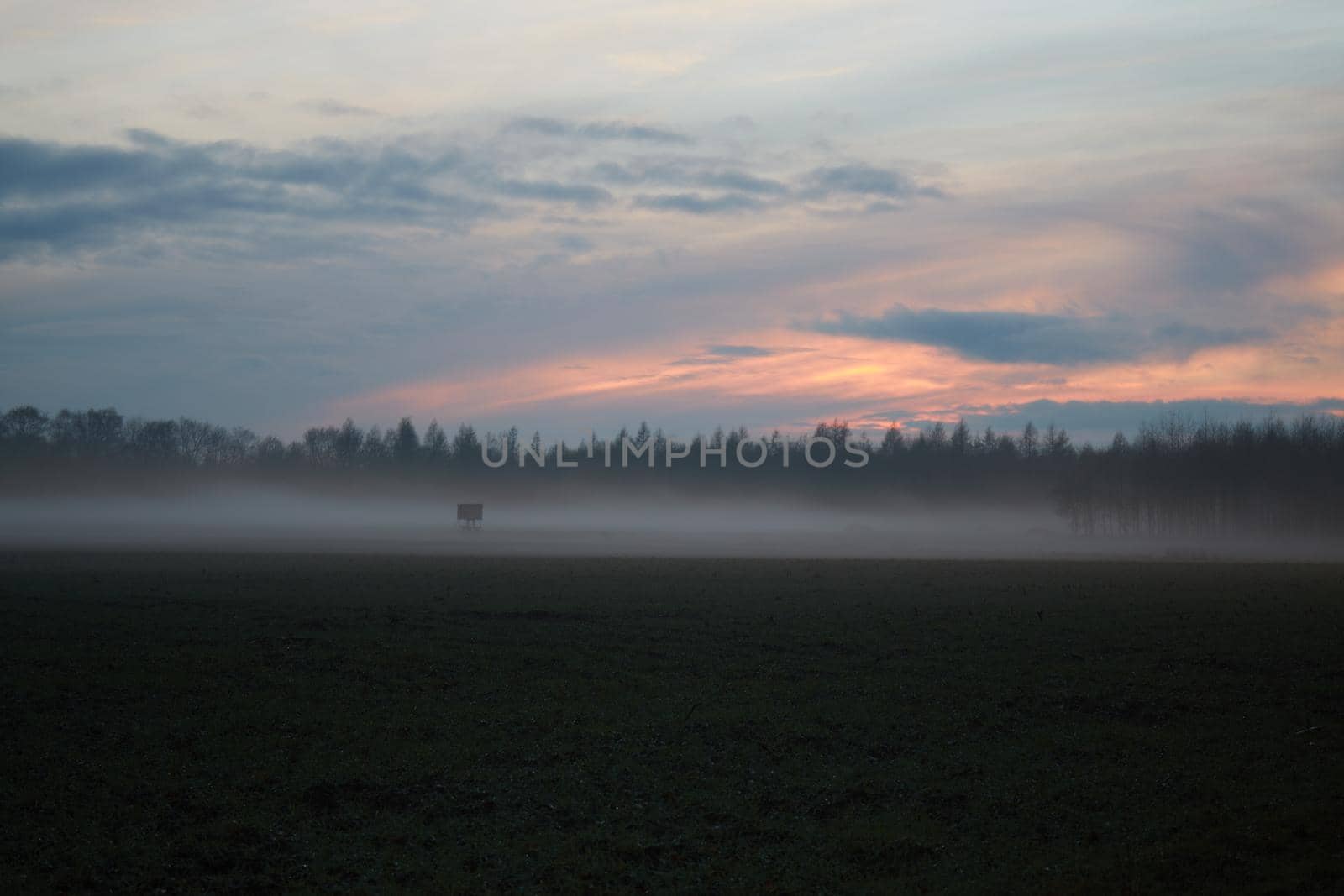 A landscape in the evening with fog and sunset