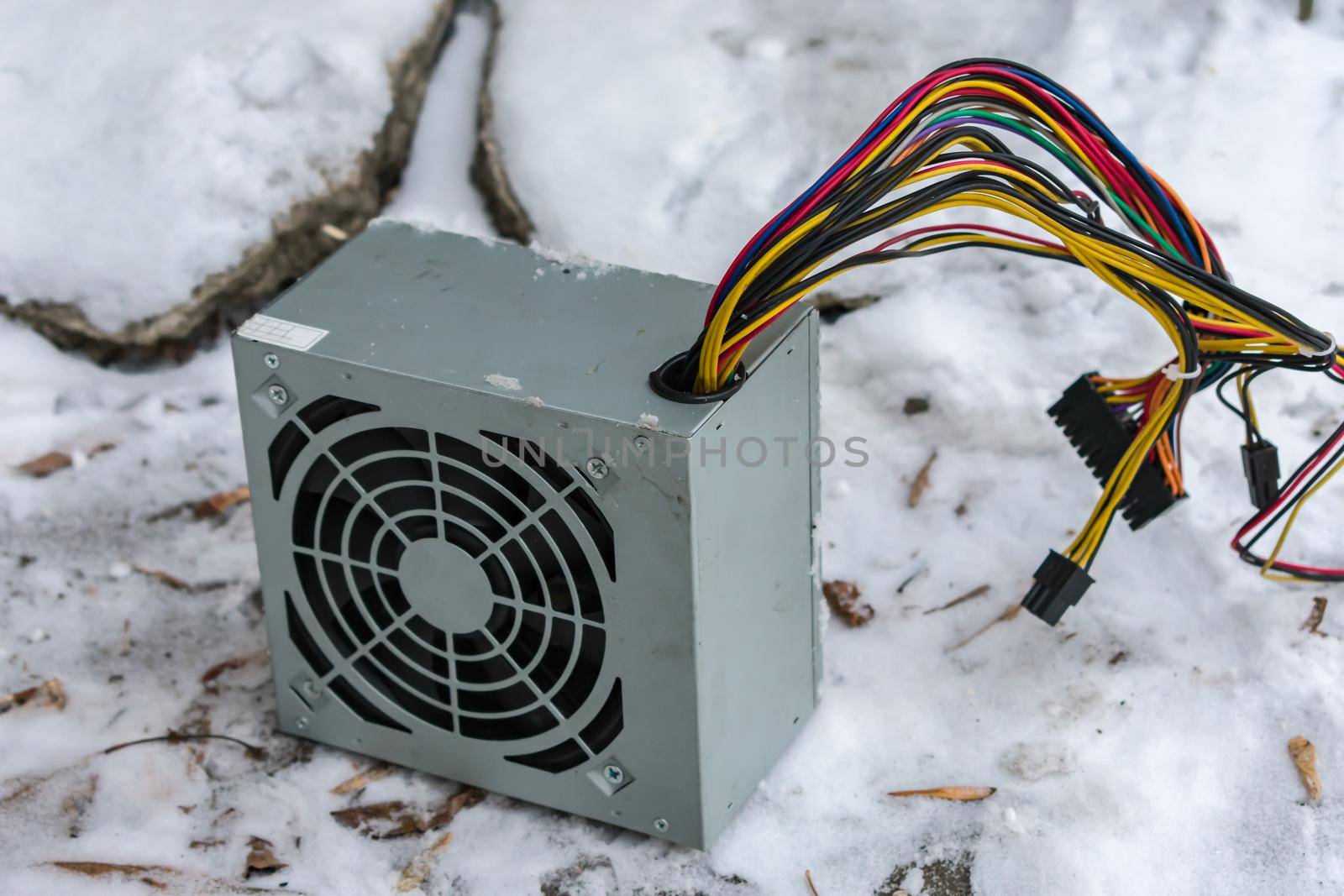 The PC power supply lies at an electronics dump in winter in the snow