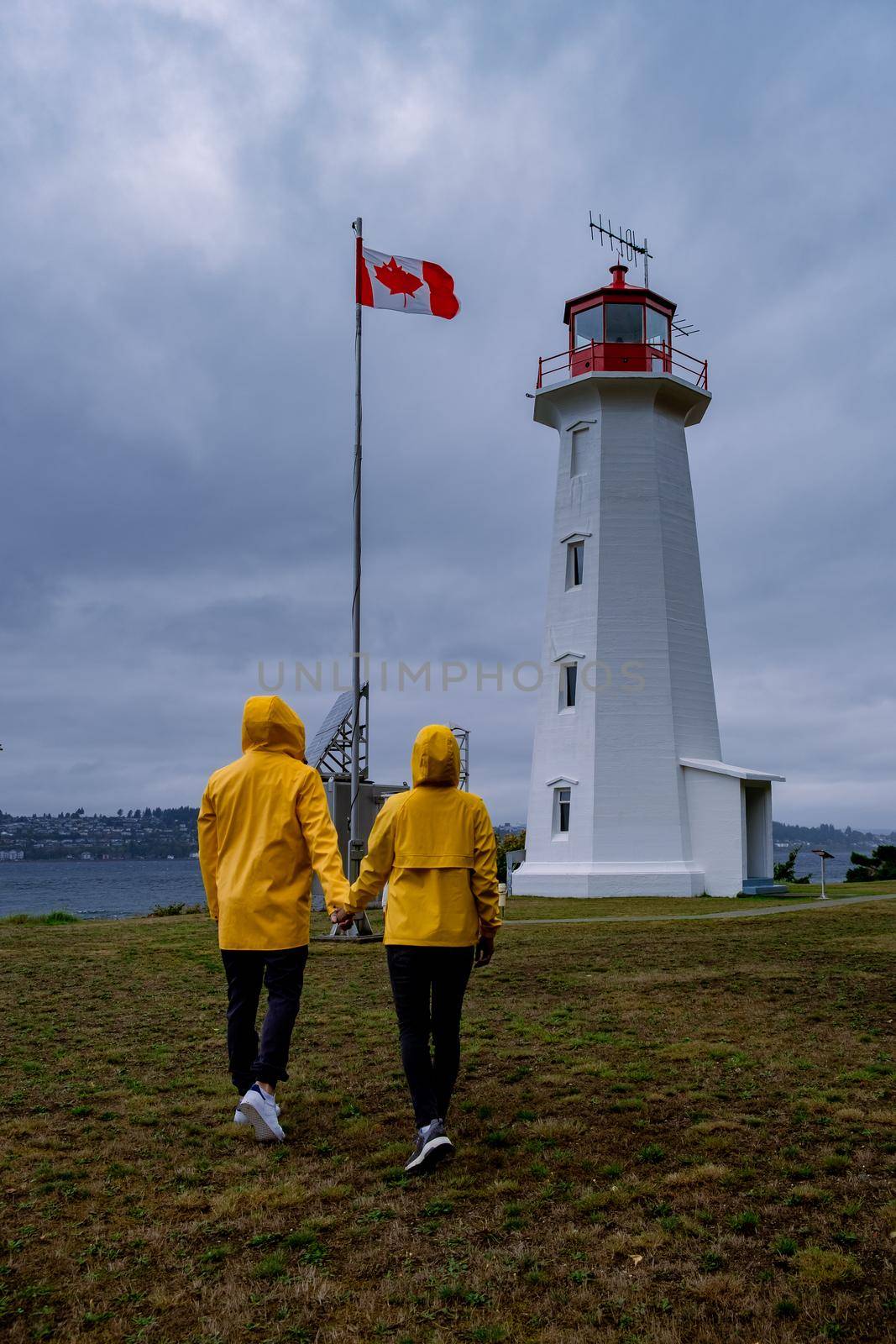 Vancouver Island, Canada, Quadra Island old historical lighthouse at Cape Mudge. couple in yellow rain coat during storm by the coast of Vancouver Island