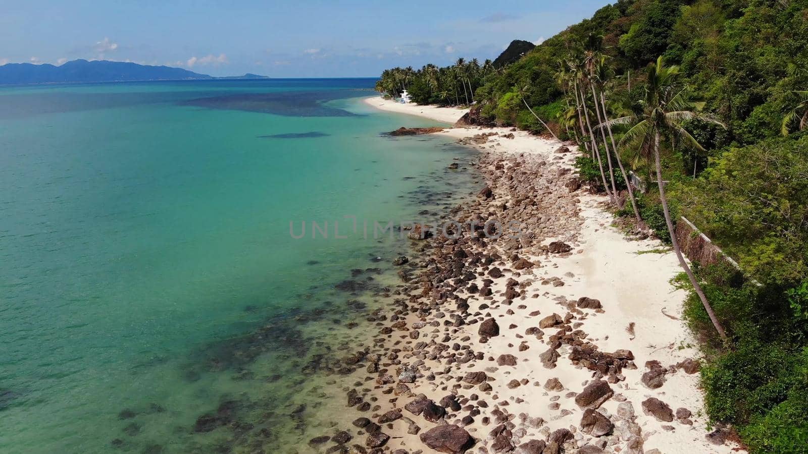 Green jungle and stony beach near sea. Tropical rainforest and rocks near calm blue sea on white sandy shore of Koh Samui paradise island, Thailand. Dream beach drone view. Relax and holiday concept
