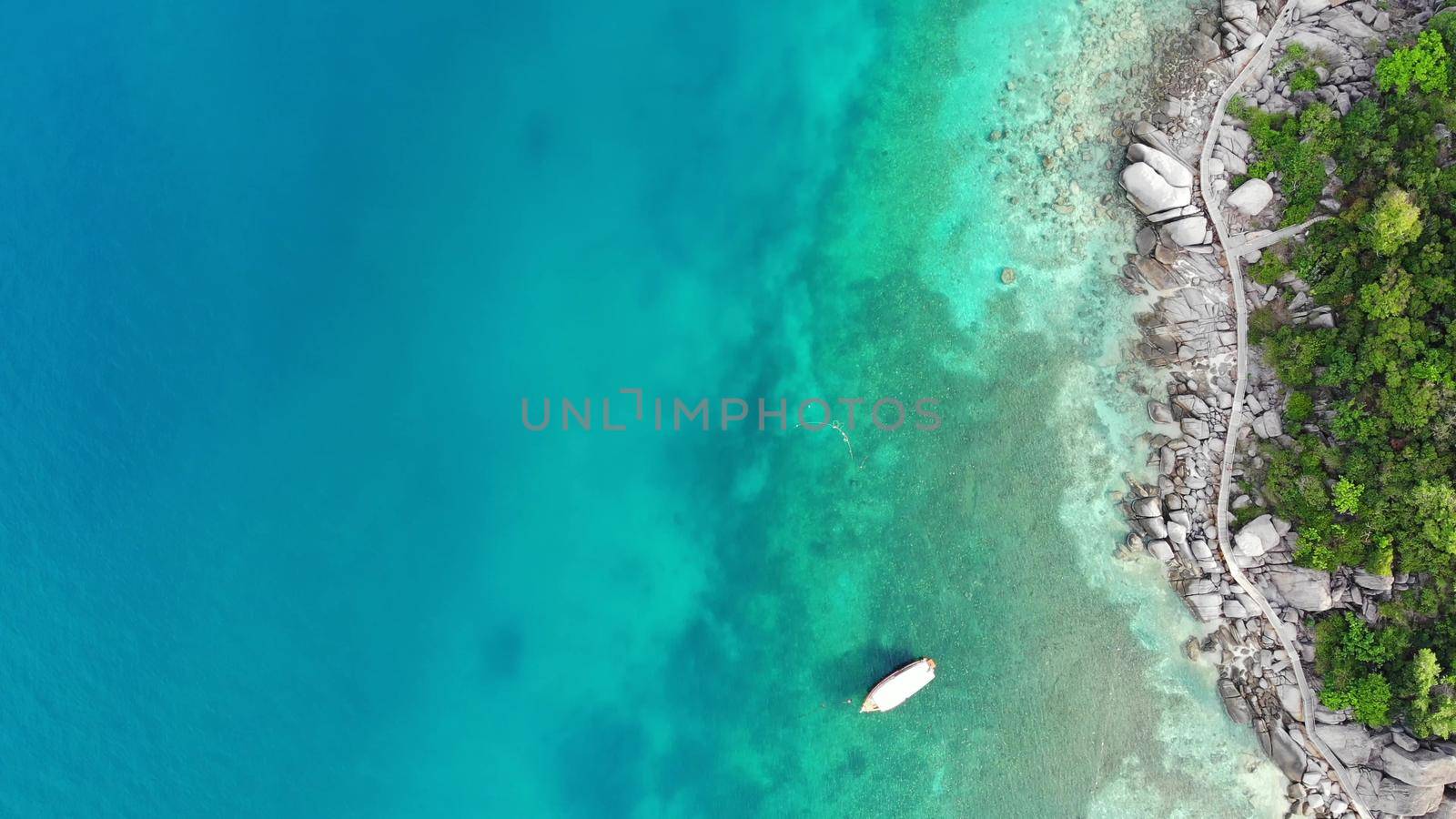 Calm colorful azure turquoise sea near tiny tropical volcanic island Koh Tao, unique small paradise Nang Yuan. Drone view of peaceful water near stony shore and green jungle on sunny day in Thailand