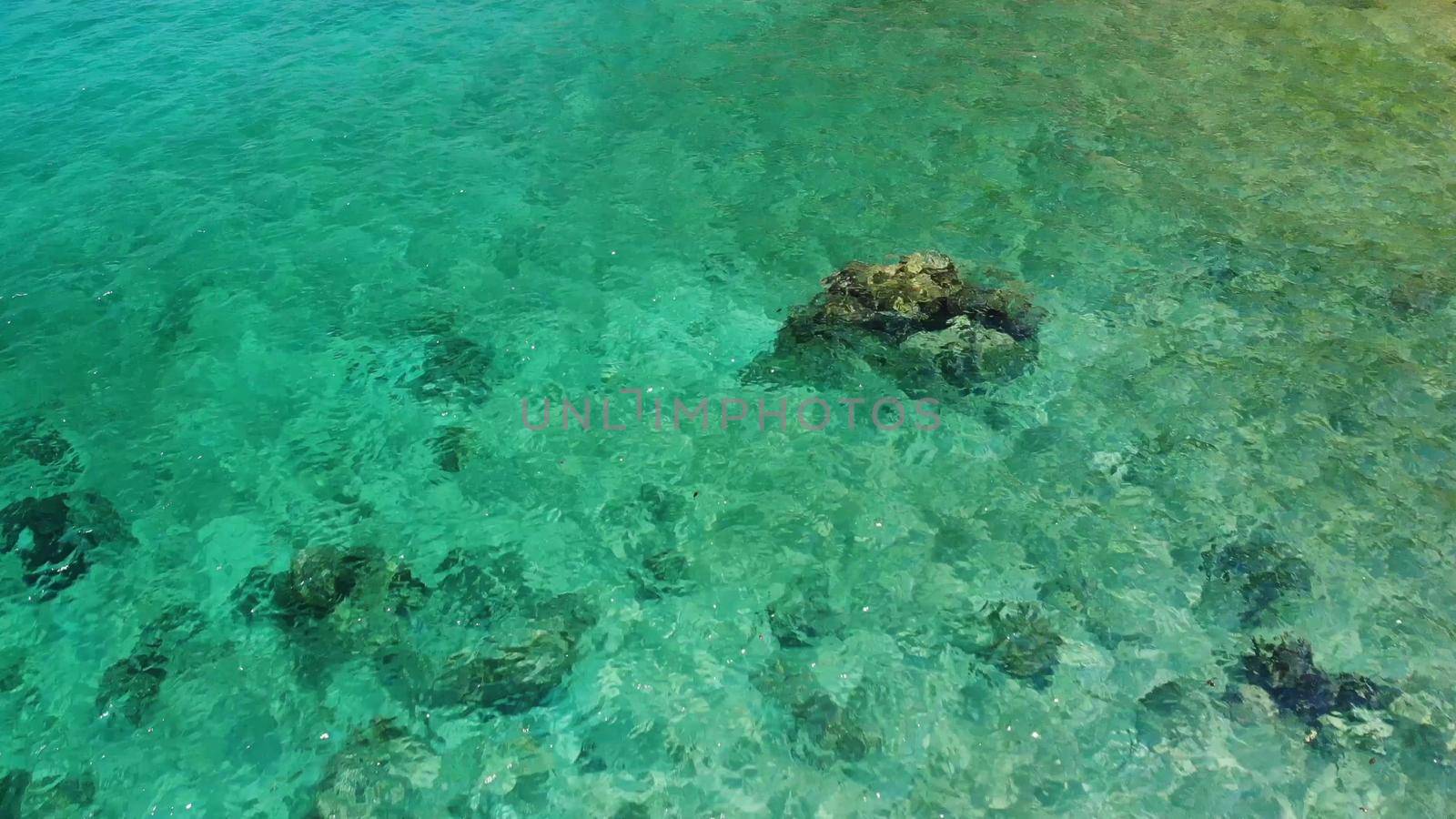Calm sea water near stones. Peaceful blue sea water and gray boulders in perfect place for snorkeling on Koh Tao Island on sunny day in Thailand. Natural background texture