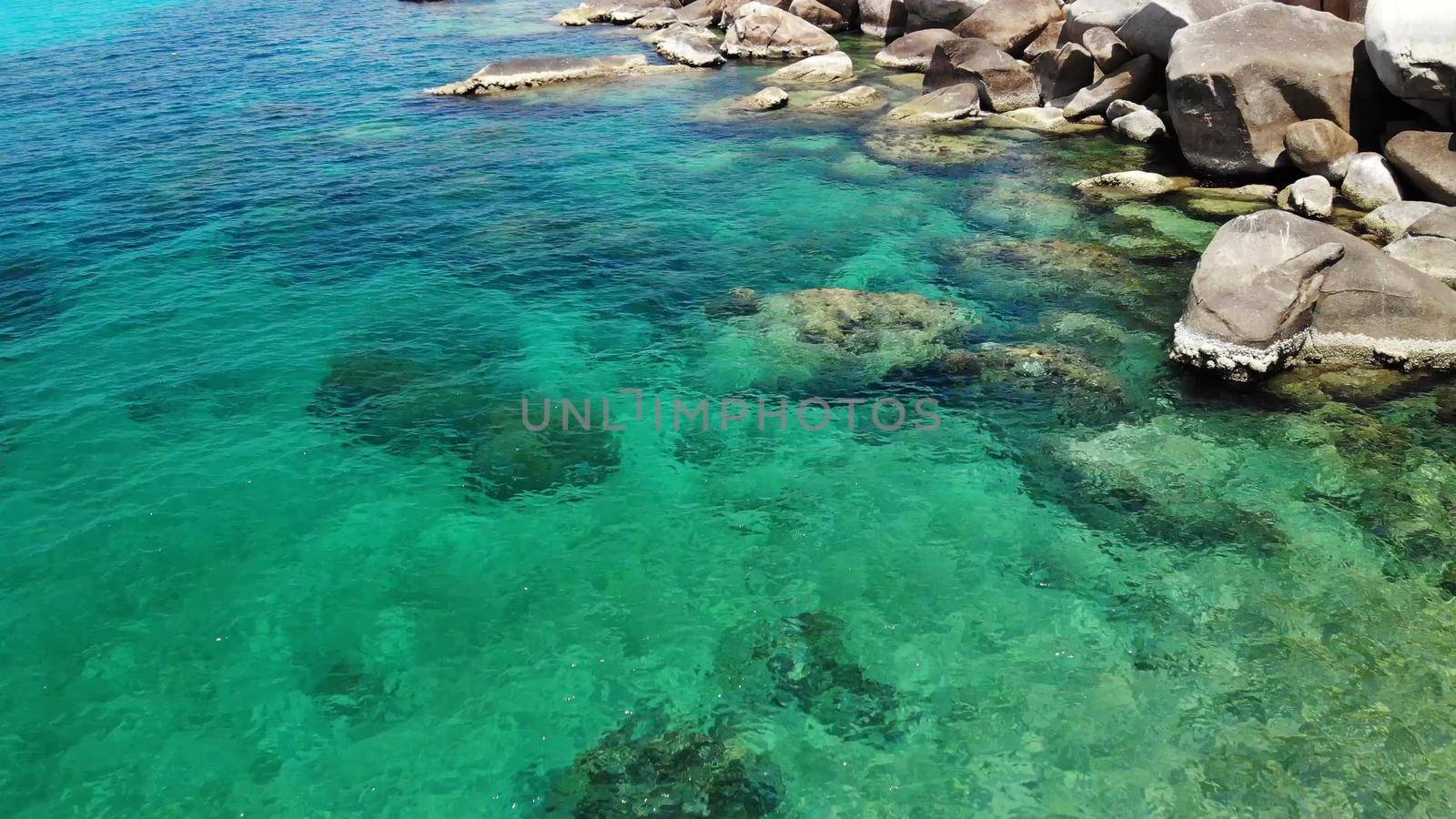 Calm sea water near stones. Peaceful blue sea water and gray boulders in perfect place for snorkeling on Koh Tao Island on sunny day in Thailand. Natural background texture