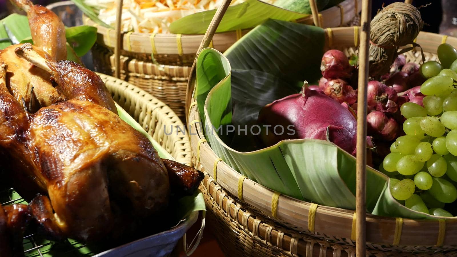 Baskets with grilled chickens and fruits. Braided baskets with tasty fried chicken and fresh fruits placed on stall in traditional Thai street diner