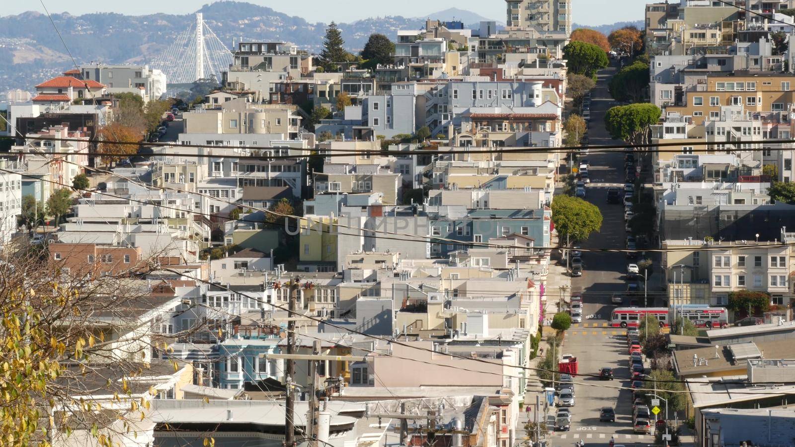 Iconic hilly street and crossroads in San Francisco, Northern California, USA. Steep downhill road and pedestrian walkway. Downtown real estate, victorian townhouses abd other residential buildings.