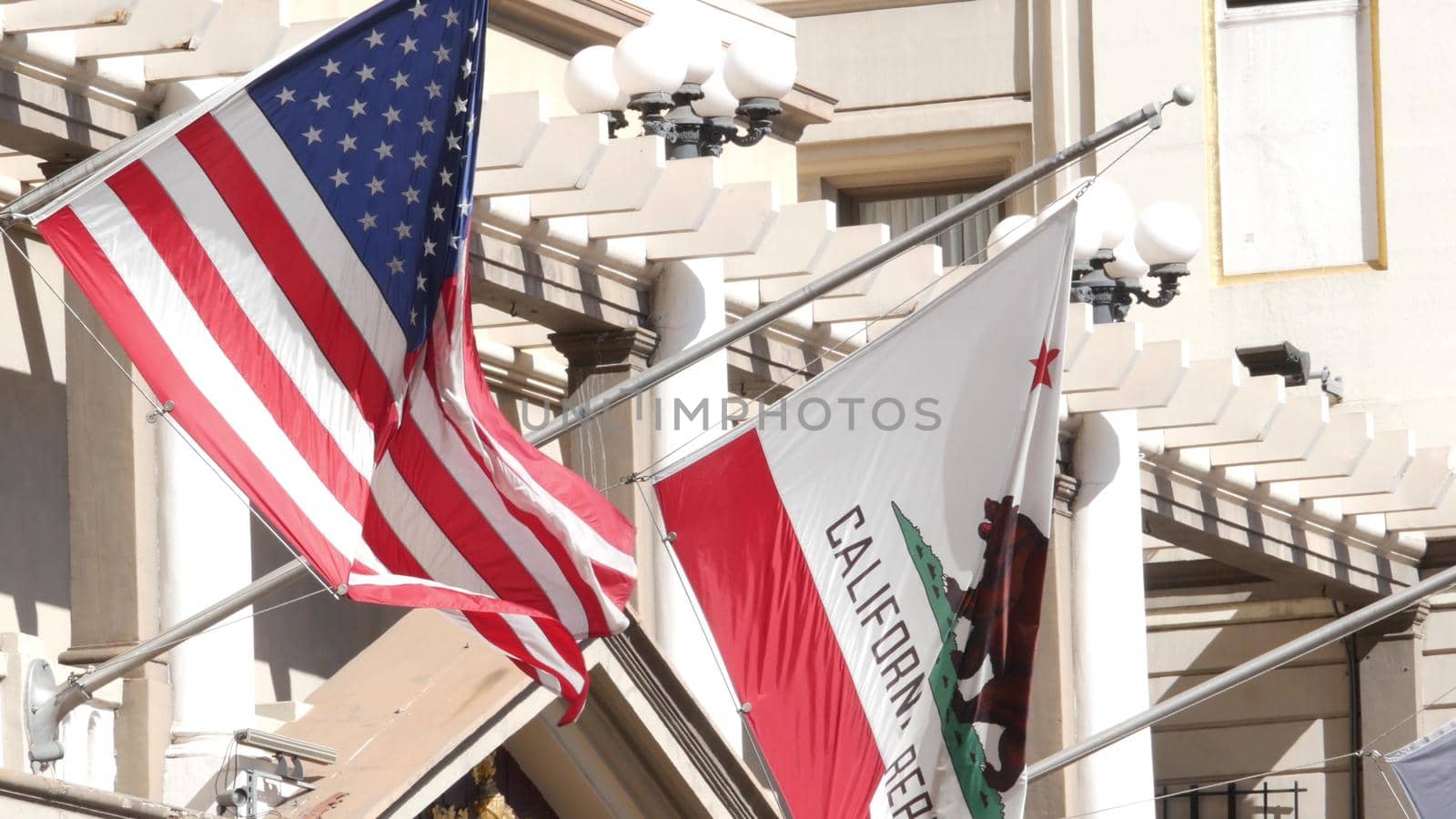 Flags of California and United States waving on flagpole in Gaslamp, center quarter of San Diego. Bear emblem of Republic and Star-Spangled Banner on flagstaff. Symbol of ptriotism and government by DogoraSun